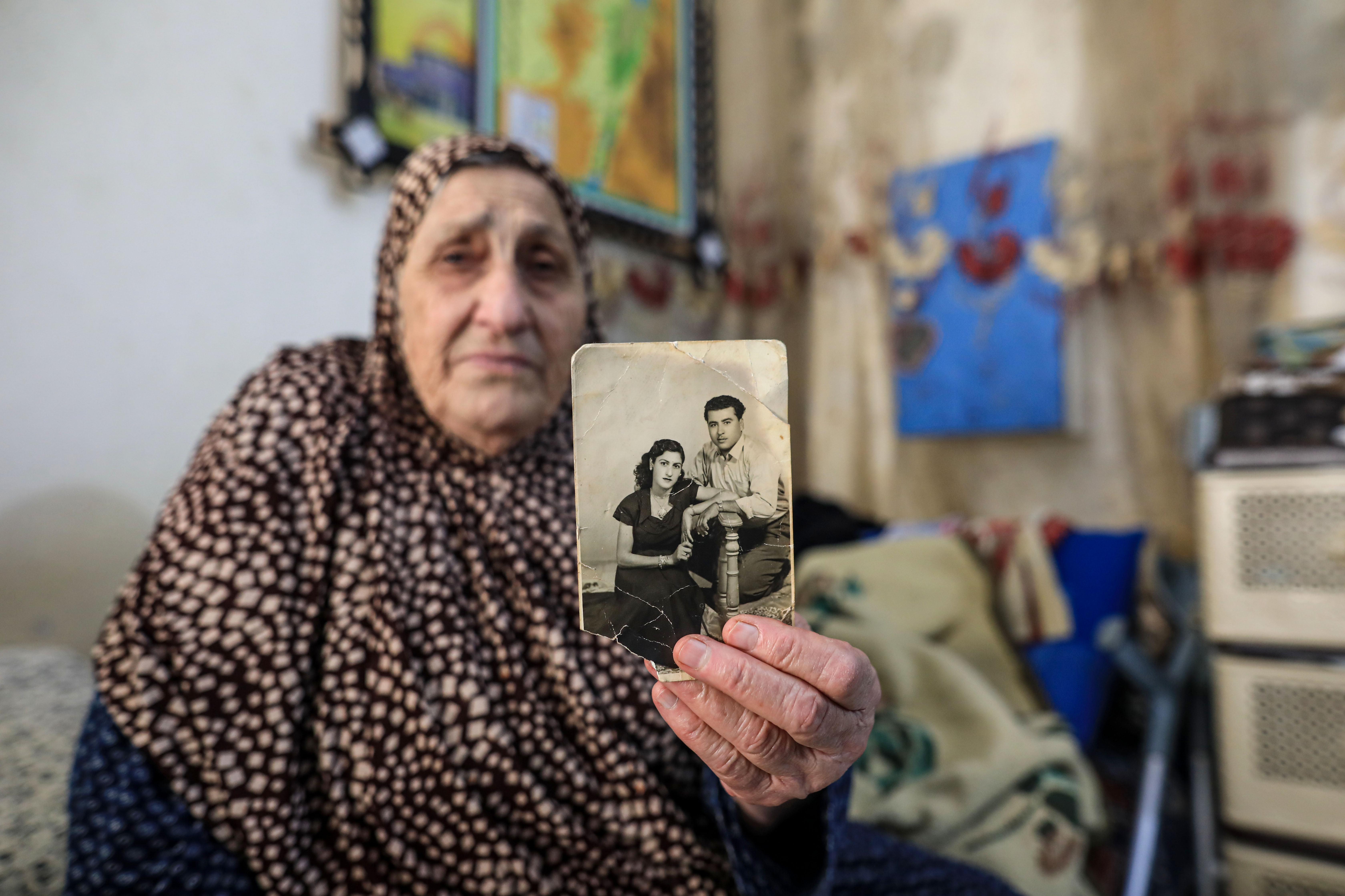 Um Khattab holds up a photo of her with her husband on their engagement day in 1948, the same year as the Nakba [Abedelhakim Abu Riash, Al Jazeera]