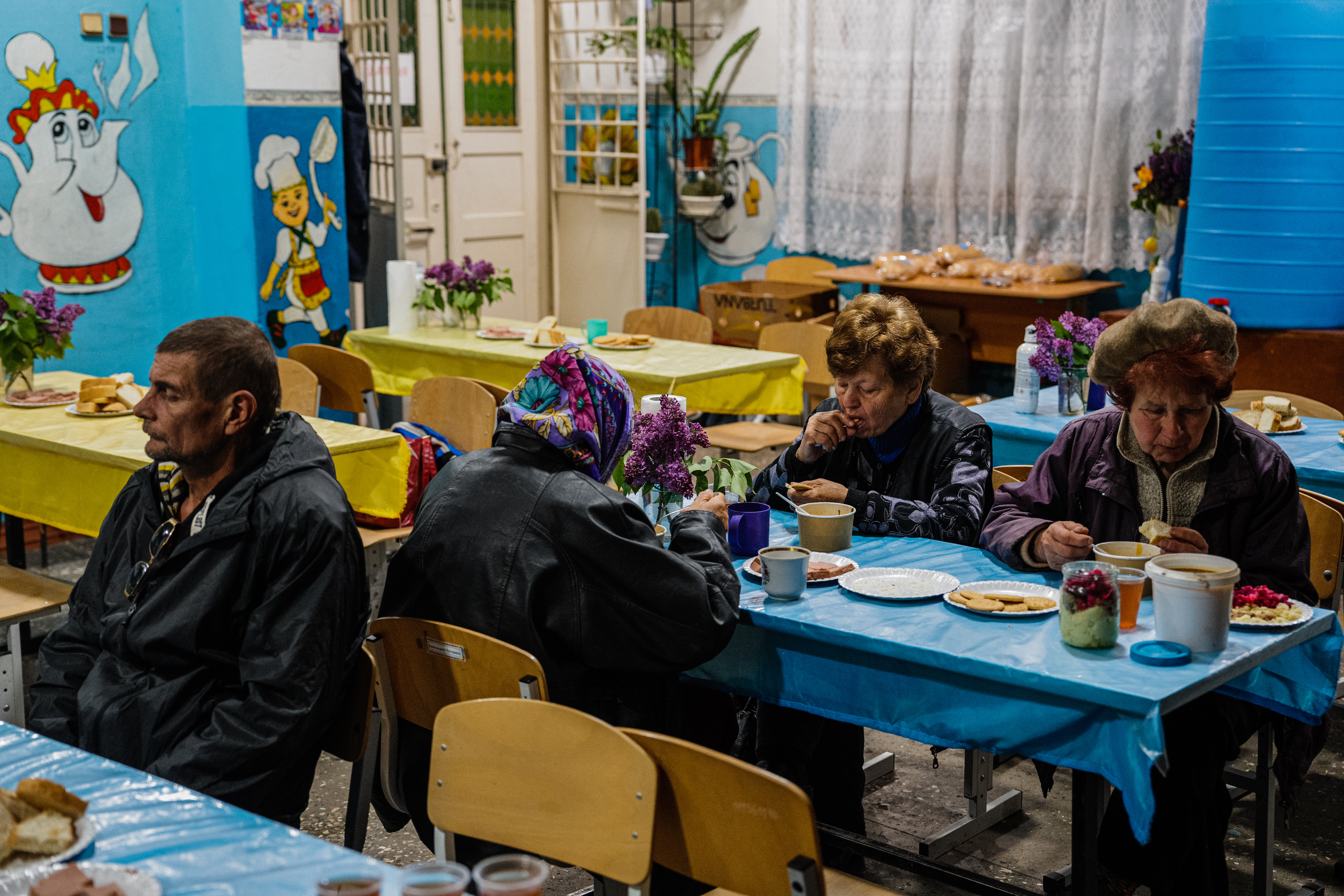 Local residents sit in a volunteer run shelter, providing access to laundry and bathroom facilities where they can warm up, charge their phones, drink hot tea and receive humanitarian aid in the town of Orikhiv, in the Zaporizhzhia region