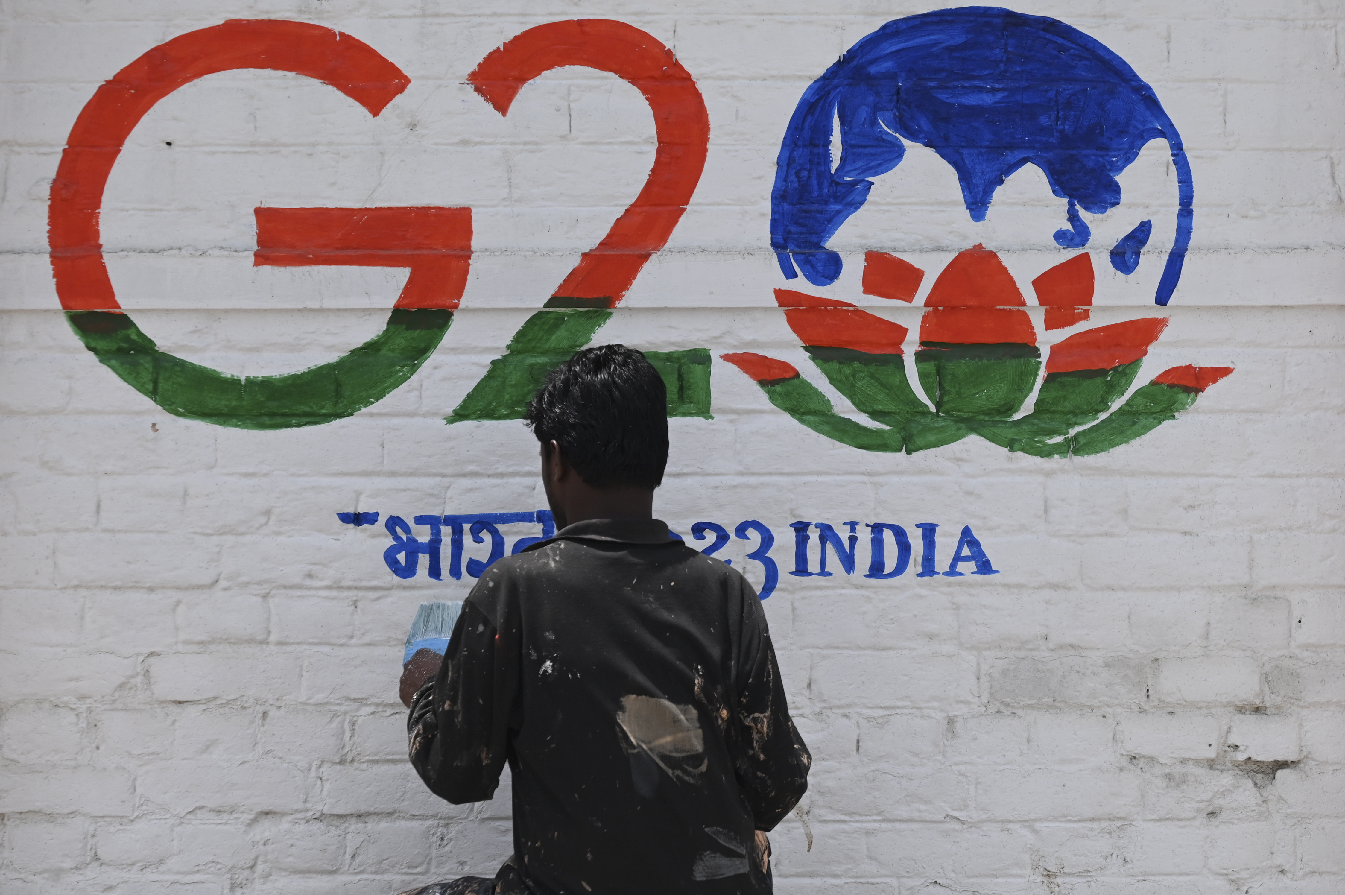 A man paint a wall with the logo of India's G20 summit in Srinagar