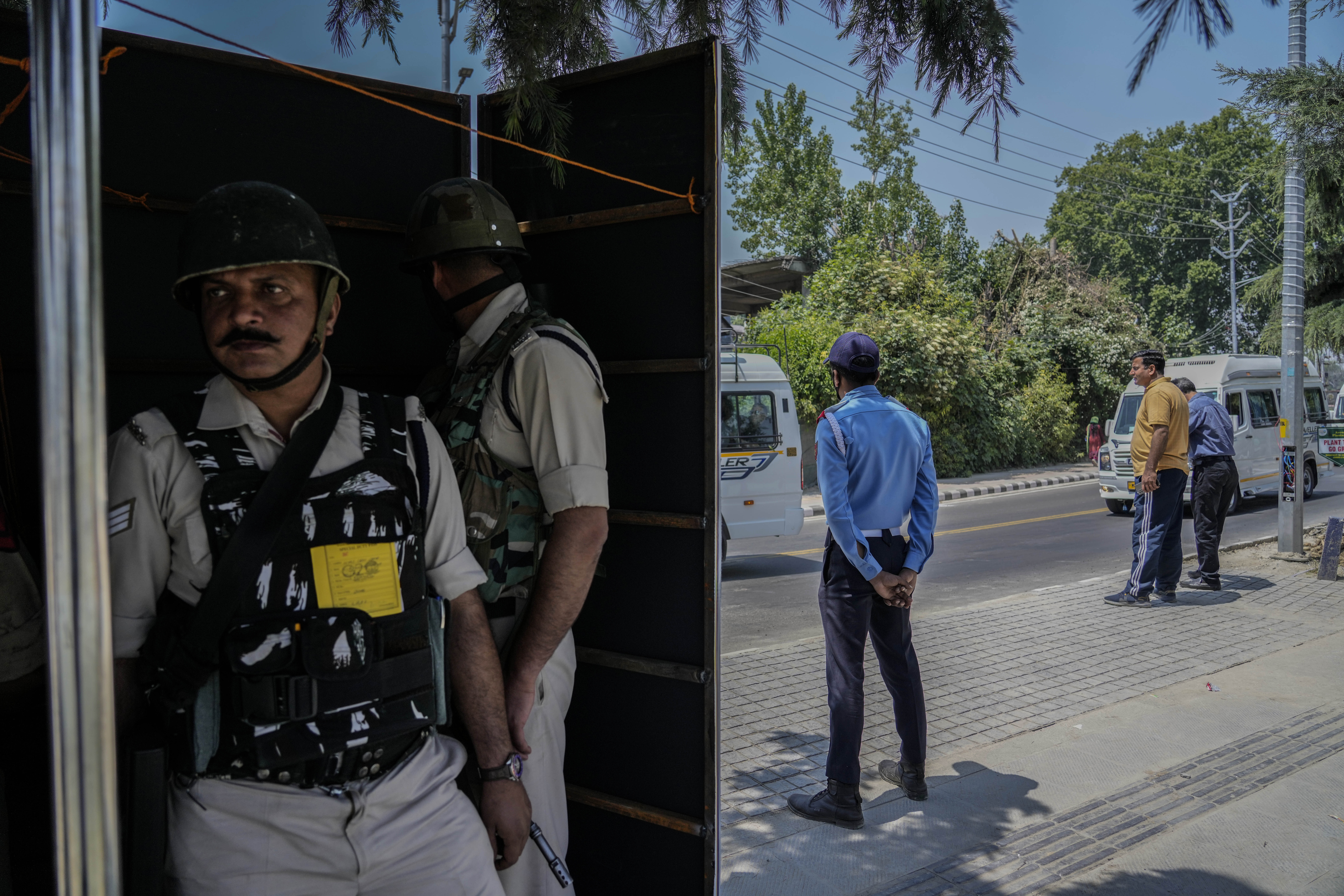 Indian paramilitary soldiers and policemen guard from behind a temporary security post as G20 delegates arrive to participate in the tourism meeting in Srinagar