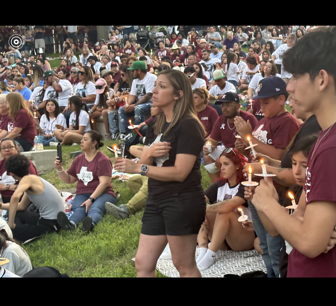 A huge crowd of people some seated and some standing holding candles in a vigil for those killed in Uvalde