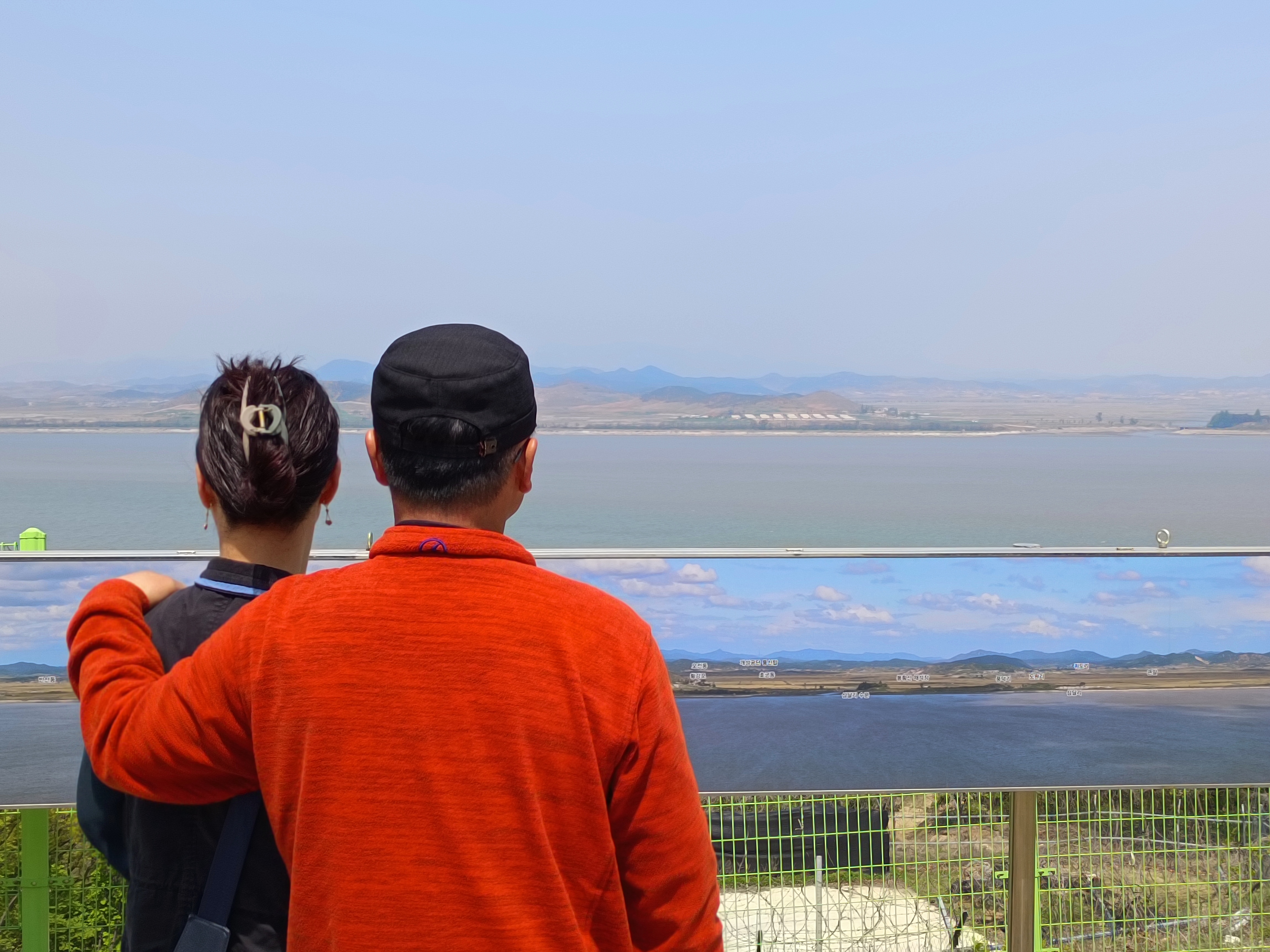Couple looking at North Korea across the Han River estuary at the Ganghwa Peace Observatory. It's a sunny day with a cloudless sky
