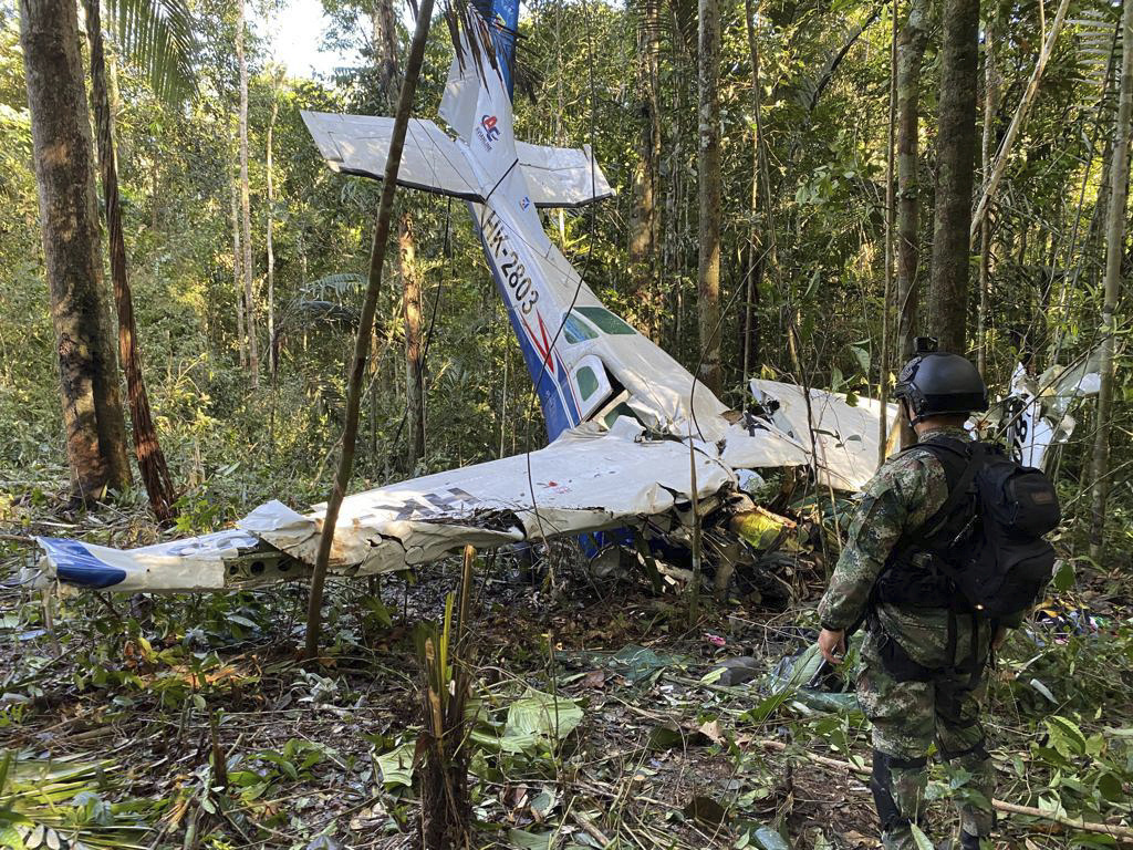 In this photo released by Colombia’s Armed Forces Press Office, a soldier stands in front of the wreckage of the Cessna 206 on May 18, more than two weeks after it crashed in the jungle of Solano in the Caqueta state of Colombia [Colombia’s Armed Forces Press Office via AP]