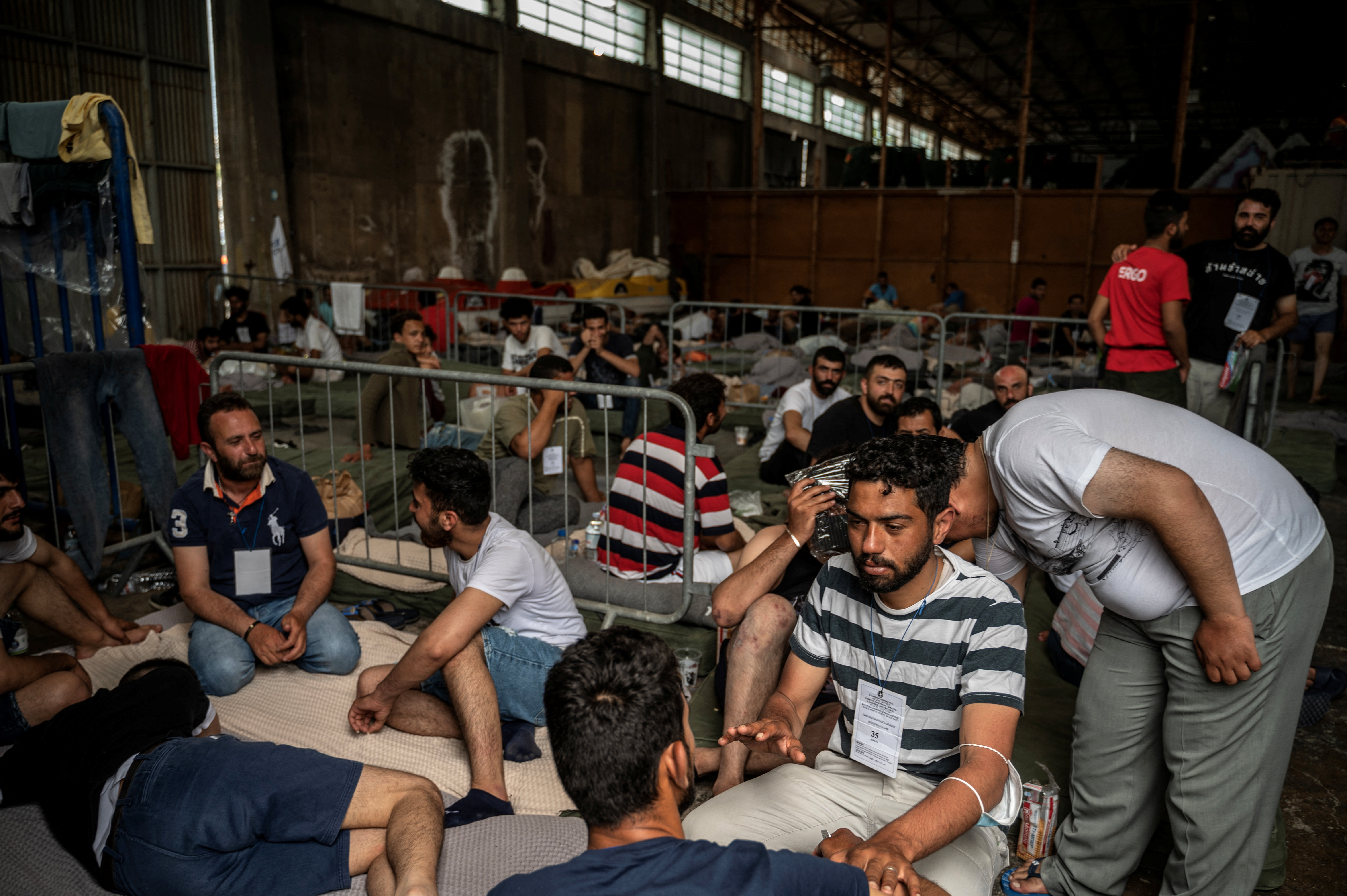 Migrants who were rescued at open sea off Greece along with other migrants, after their boat capsized, are seen inside a warehouse, used as shelter, at the port of Kalamata, Greece, June 15, 2023. Angelos Tzortzinis/Pool via REUTERS