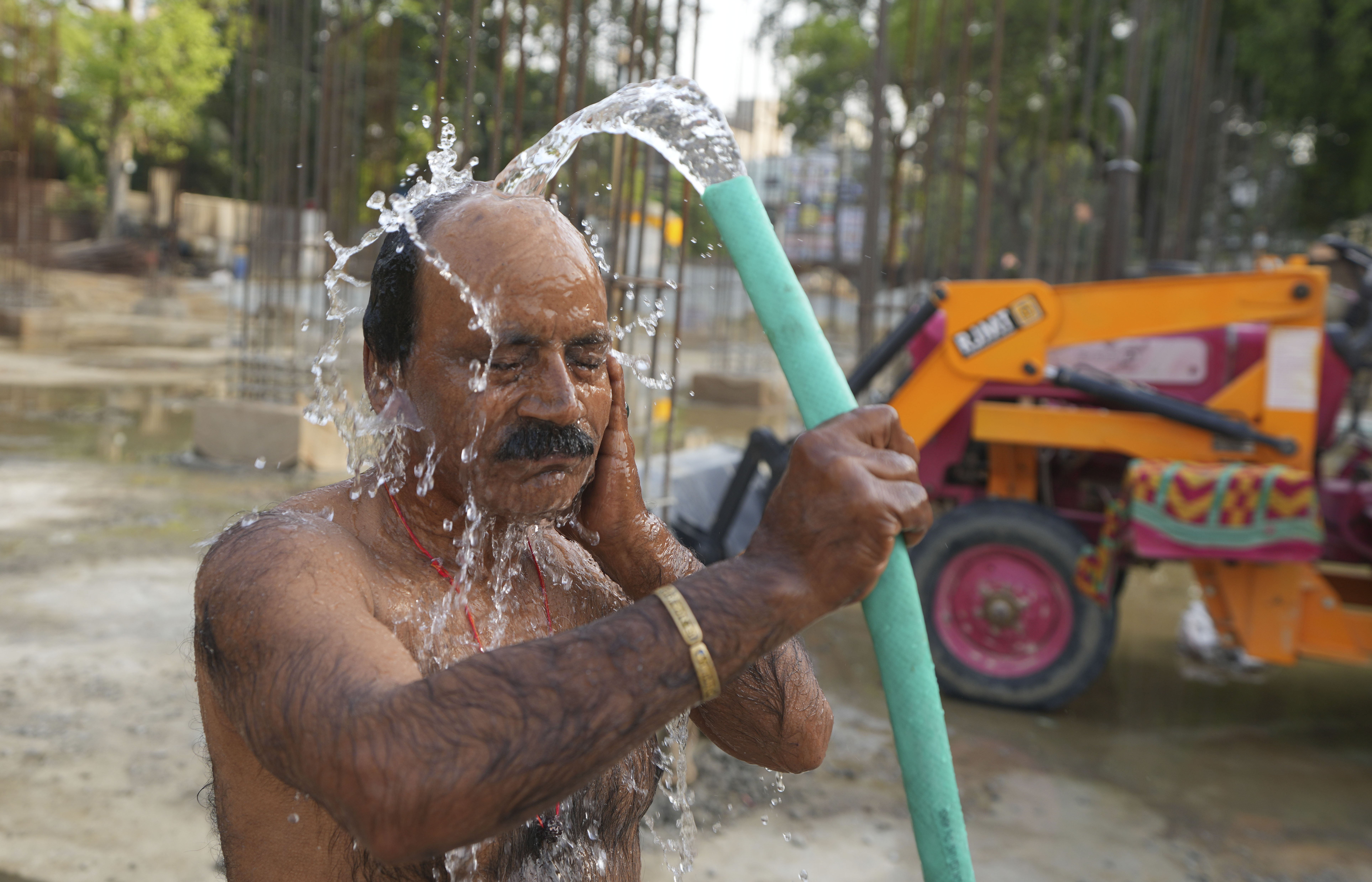 An Indian worker bathes at a building construction site as he tries to cool off on a hot day in Prayagraj