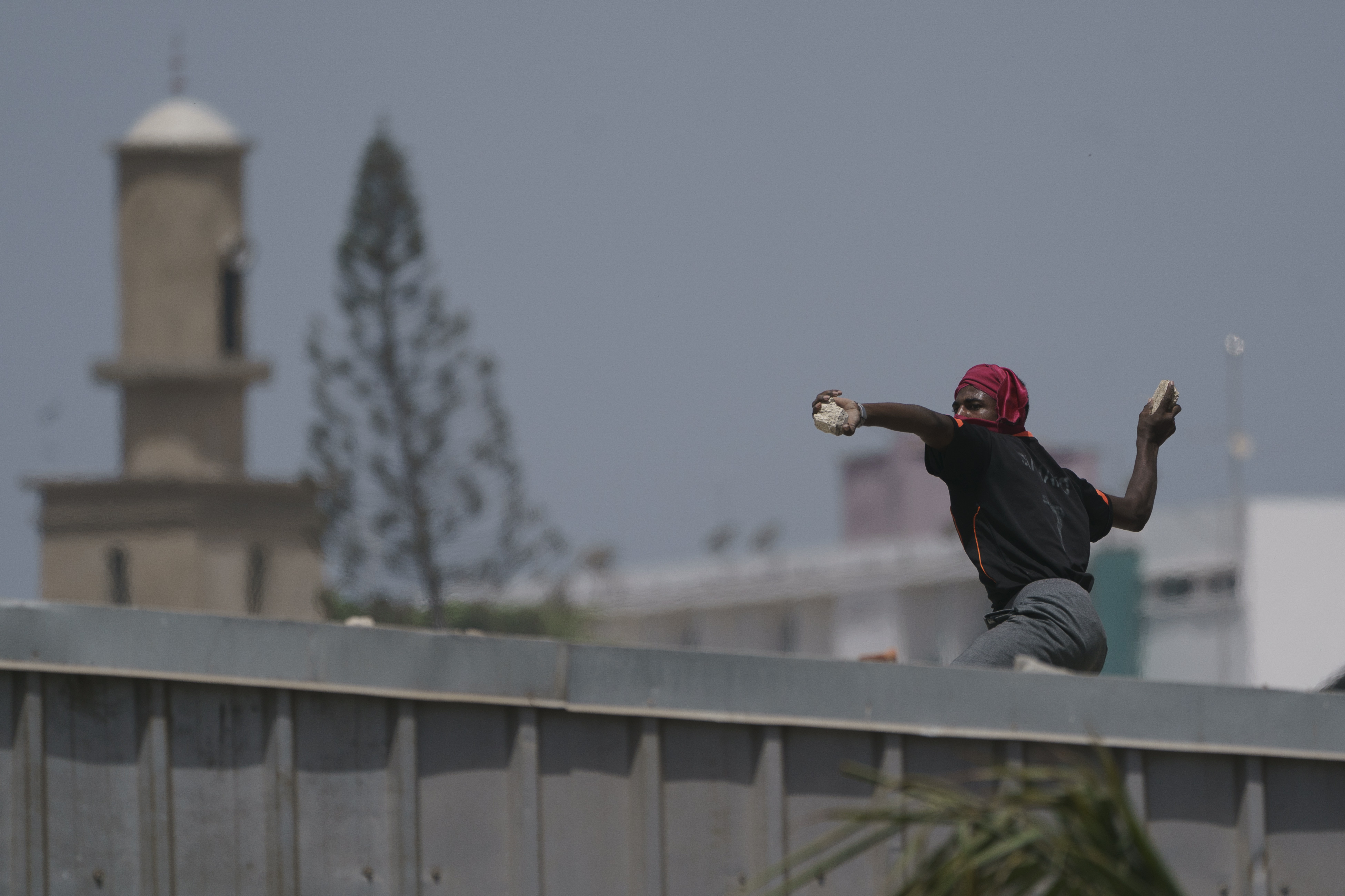 A demonstrator throws a rock at riot policemen during a protest at the Cheikh Anta Diop University campus in Dakar, Senegal,