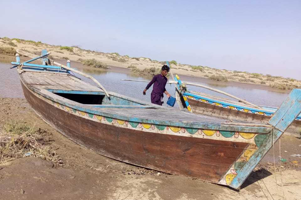 Murtaza Jati stands next to his boat