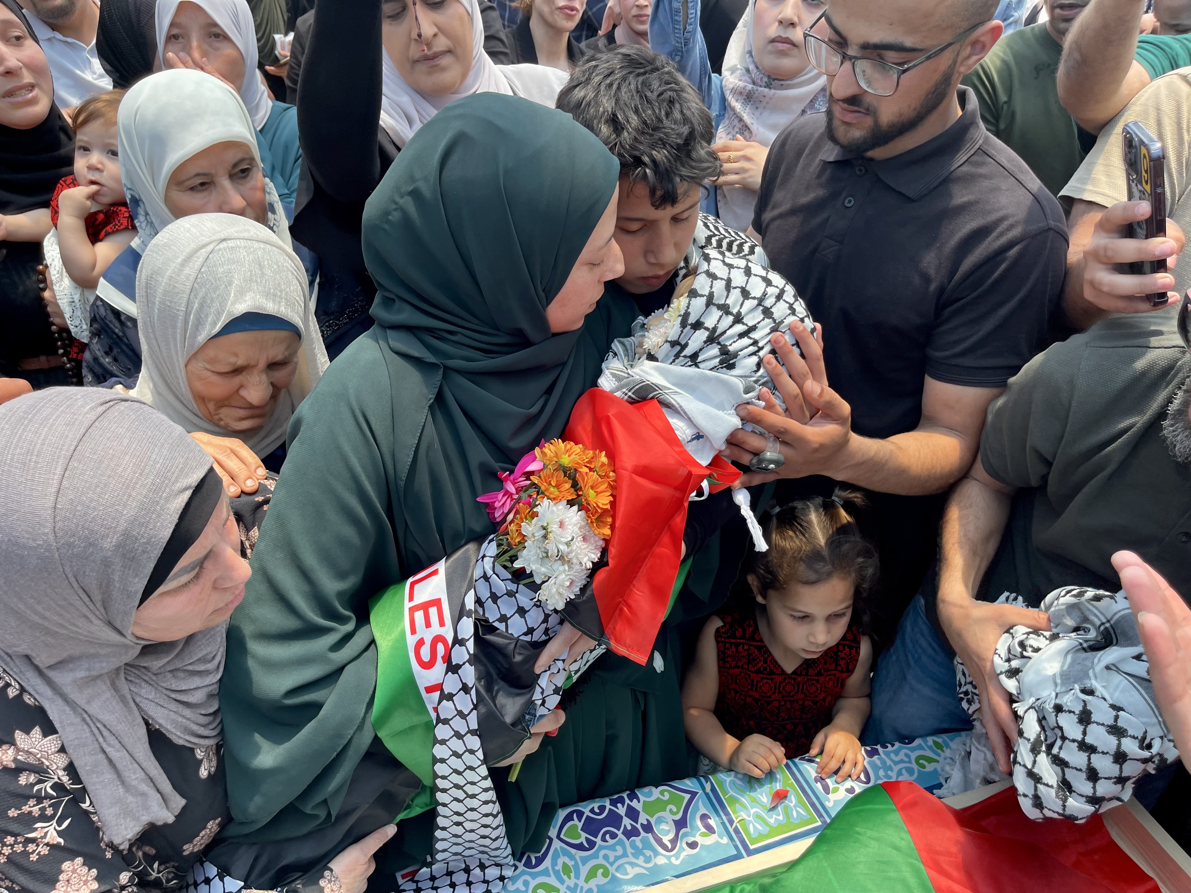 A mother kisses her shrouded toddler, who is about to be buried