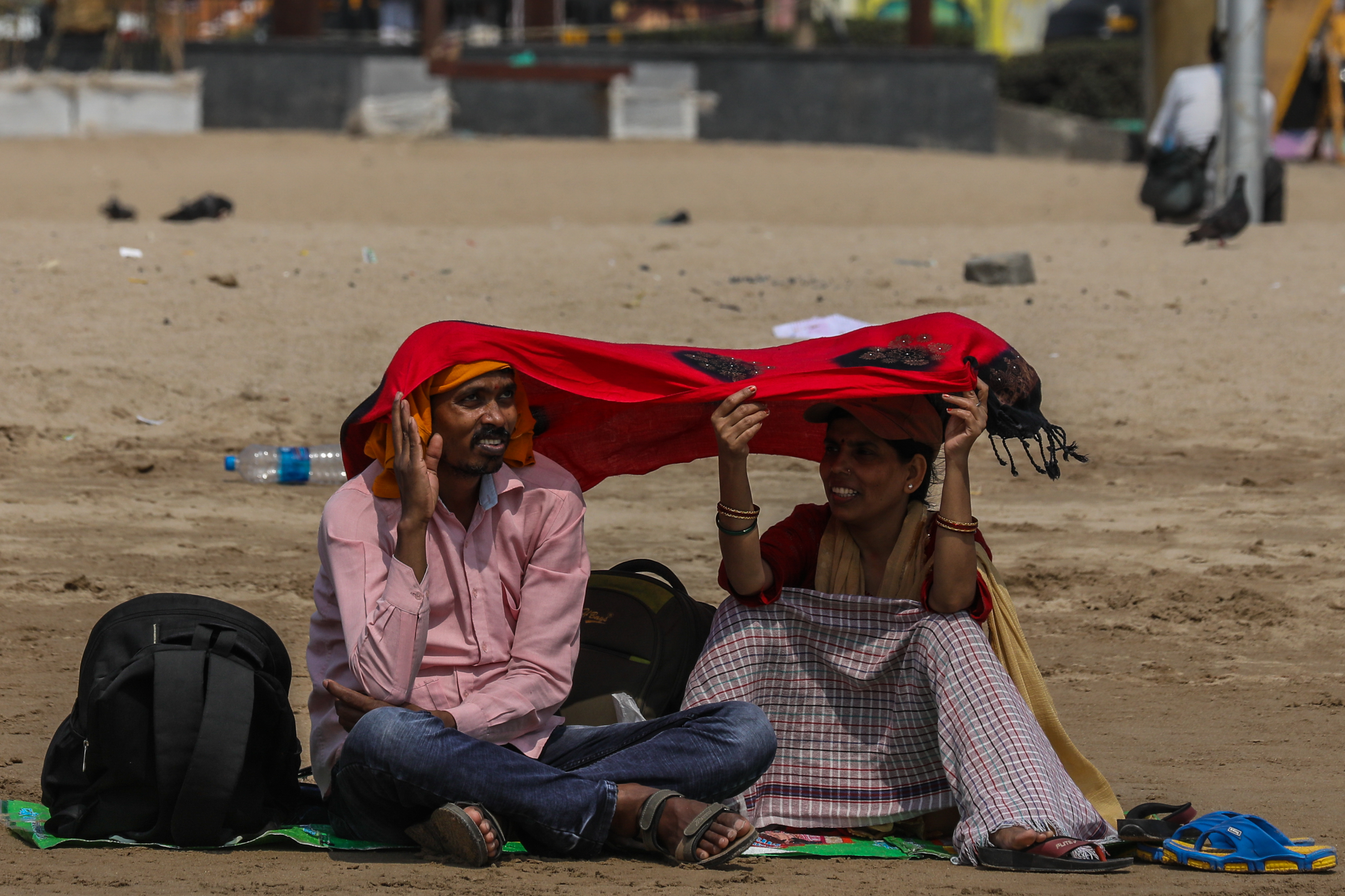 epa10576844 A couple use scarf to avoid the heat wave on a hot afternoon at Juhu beach in Mumbai, India, 17 April 2023. India Meteorological Department (IMD) issued a heat wave warning to several parts of India. EPA-EFE/DIVYAKANT SOLANKI