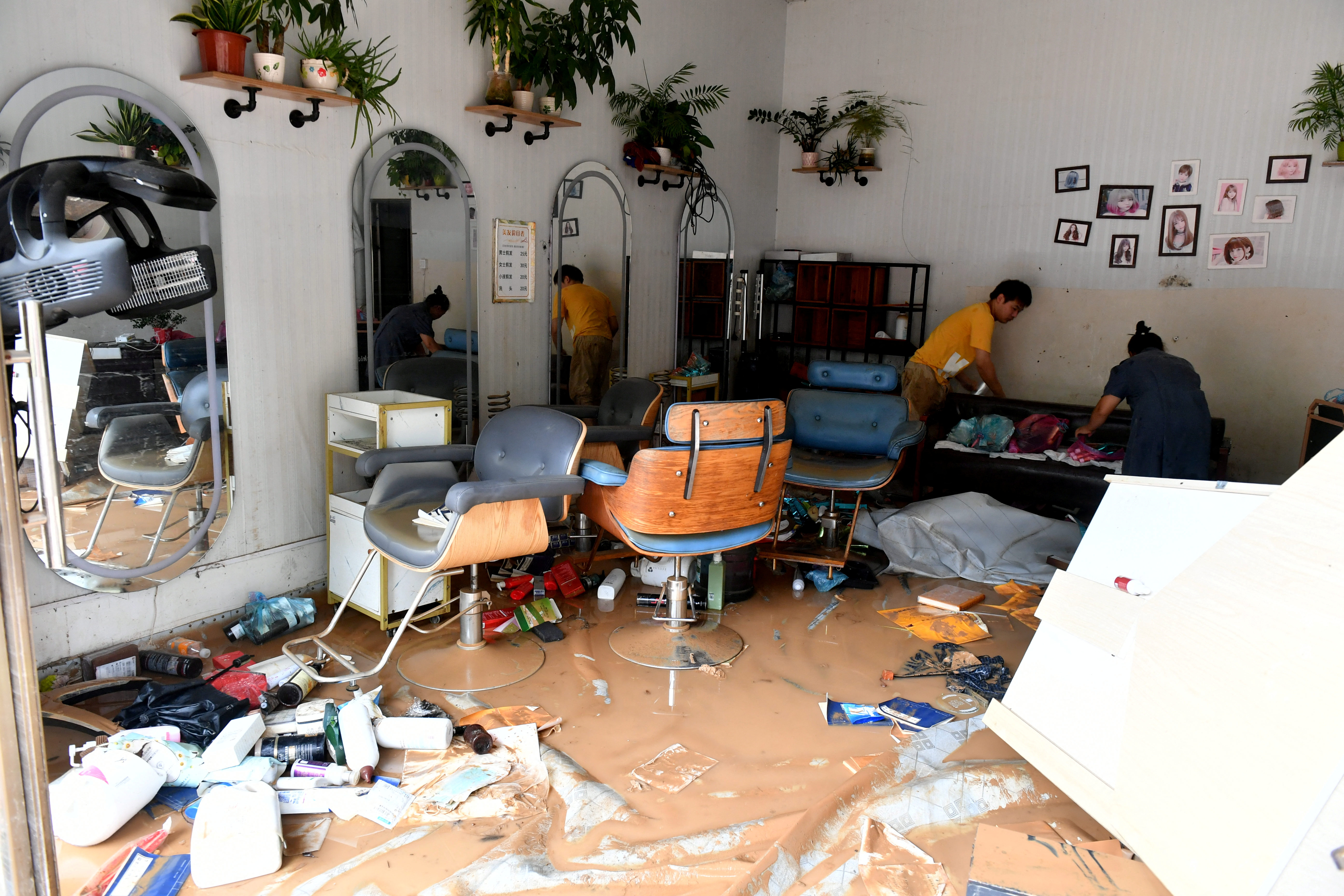 People clean a flooded shop after Typhoon Doksuri made landfall