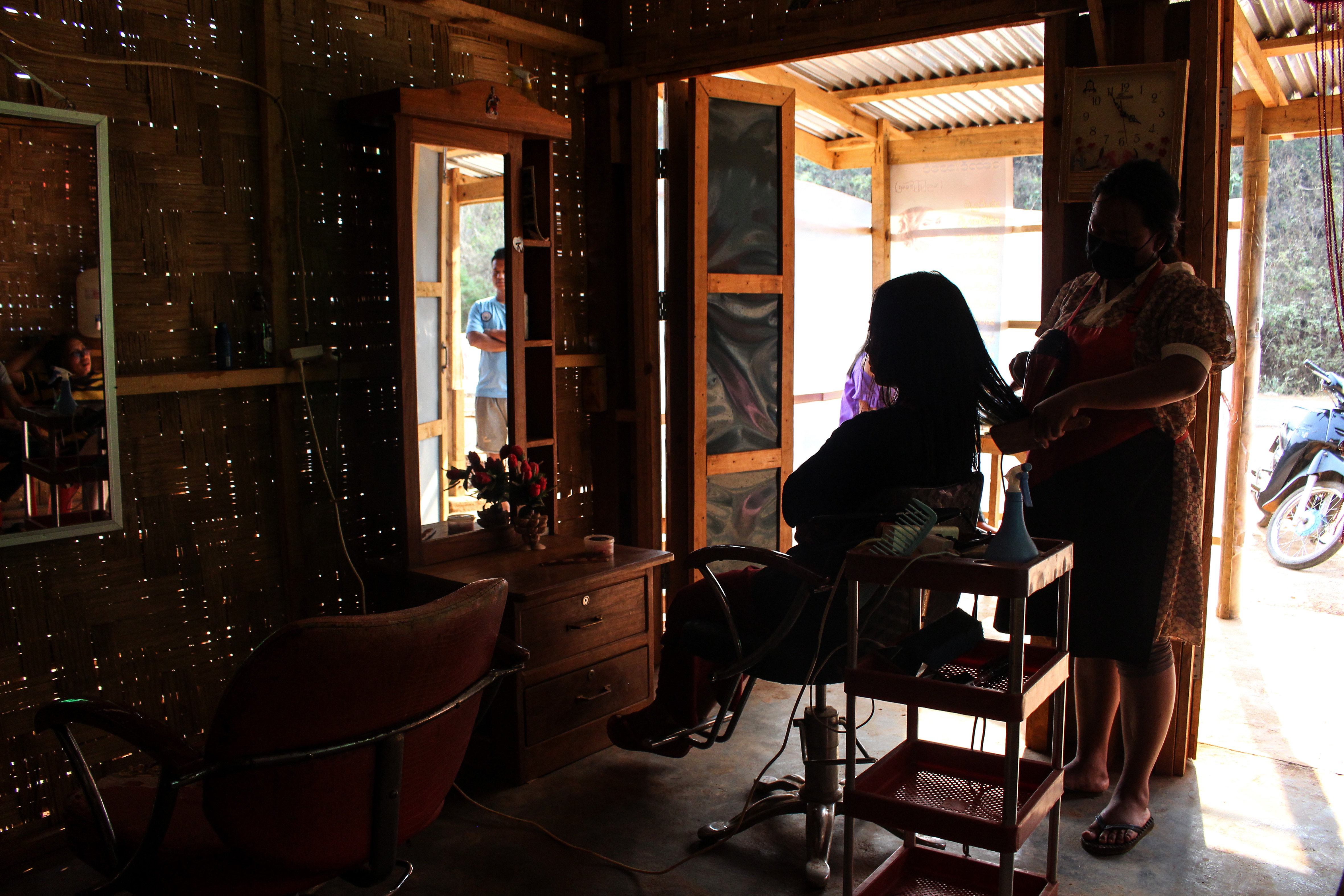 Hairdresser Caroline tends to a customer at her salon in Demoso township, Kayah state. She set up her business in the rebel-held area after fleeing fighting between armed groups and Myanmar's military in May 2021