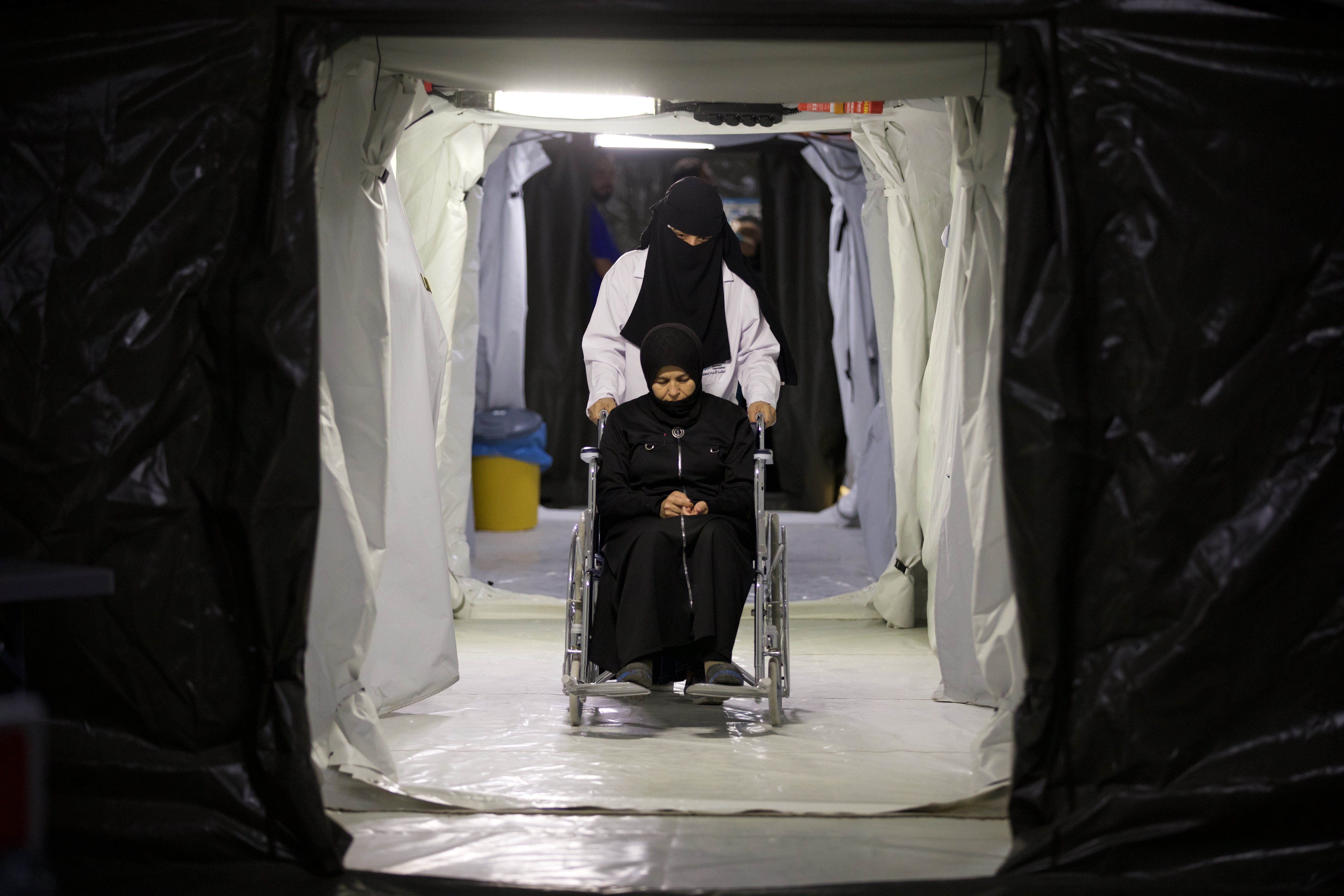 A patient in a wheelchair is guided by an employee through the Amanos Hospital