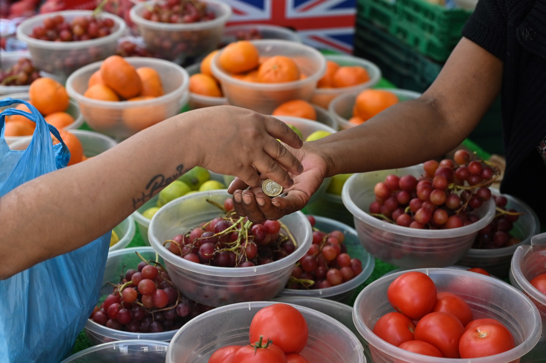 A customer pays after buying some fruits and vegetables at a street market in High Wycombe