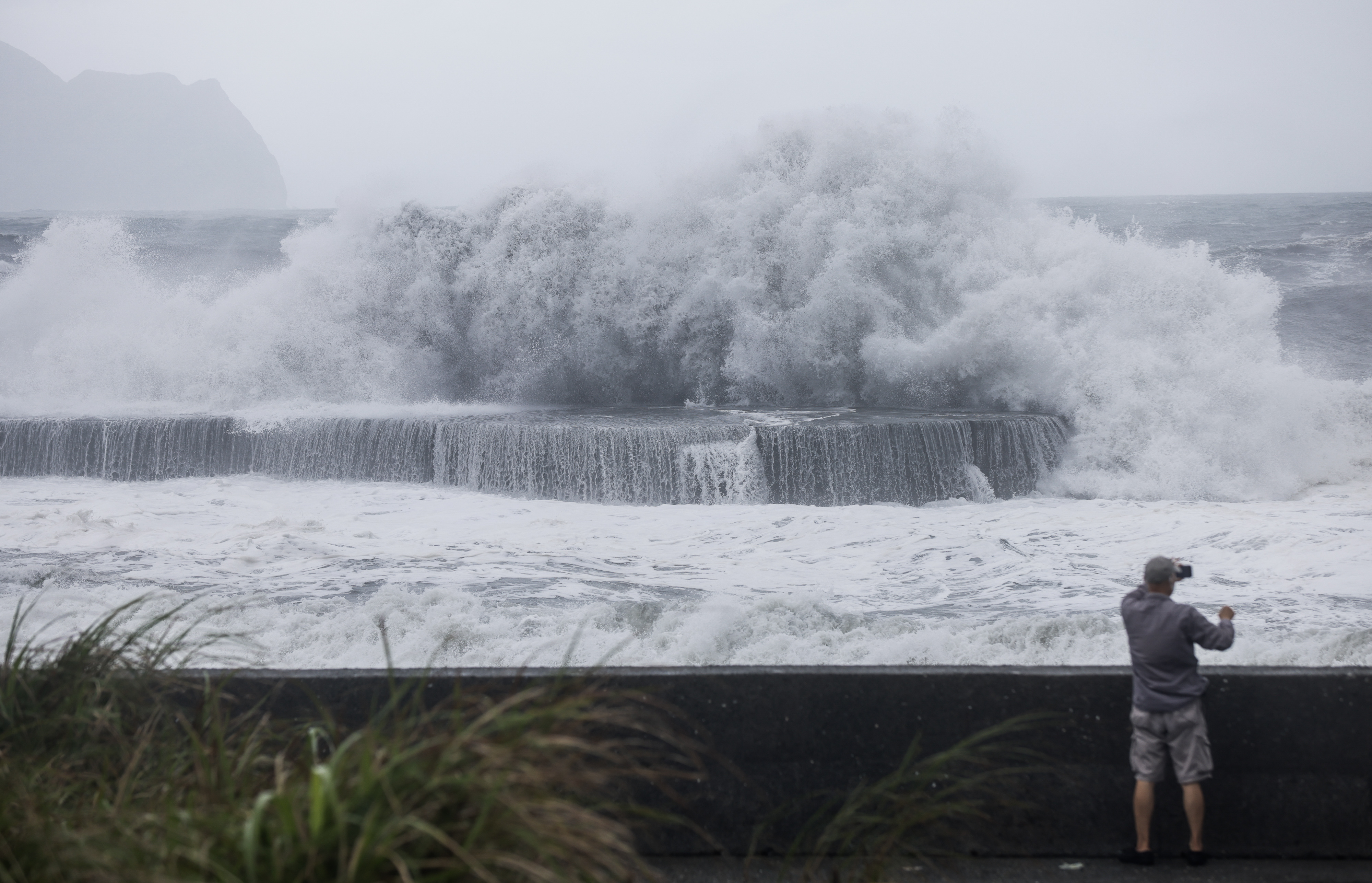 A man takes pictures of huge waves in Yilan as Haikui makes landfall in eastern Taiwan on September 3, 2023