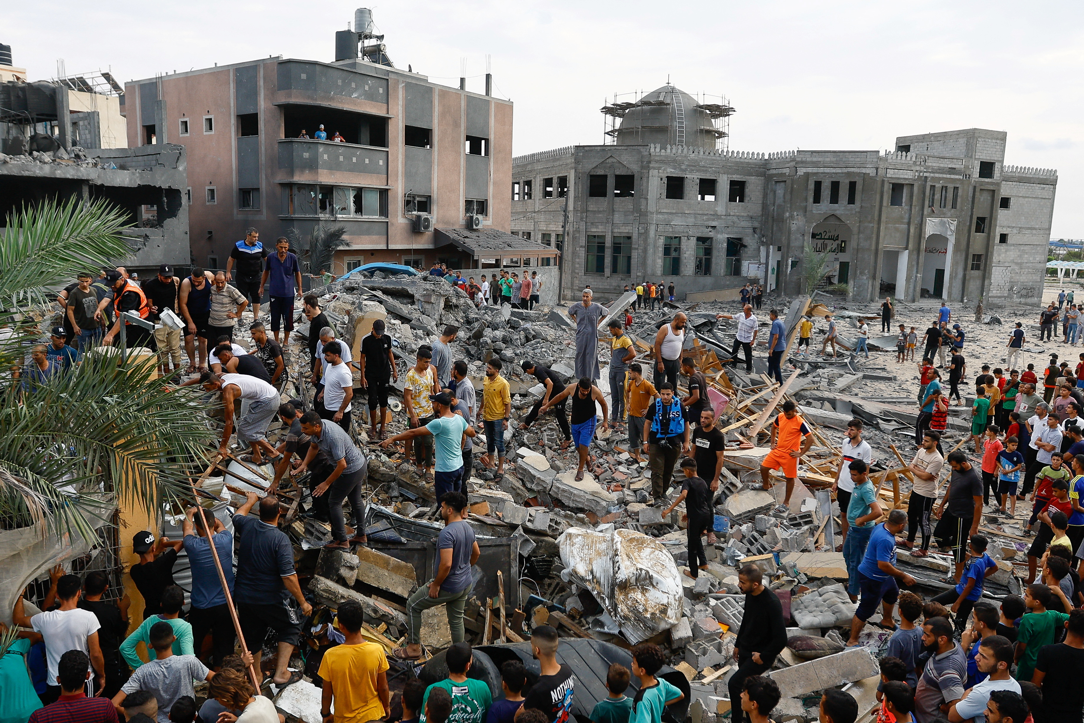 Palestinians walk among the rubble of a building destroyed in Israeli strikes, in the southern Gaza Strip