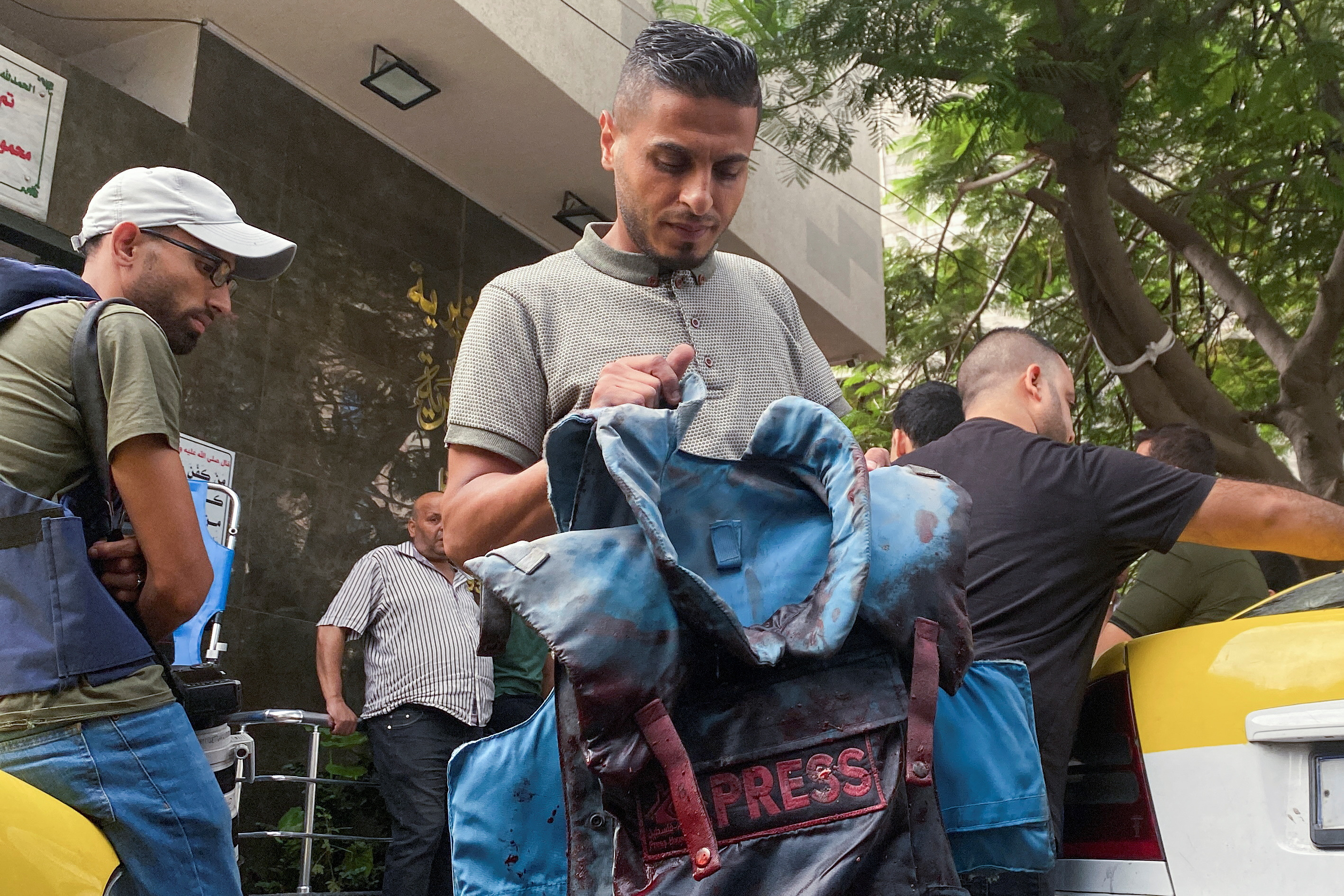 A man carries a blood-stained flak jacket belonging to Palestinian journalist Mohammed Soboh