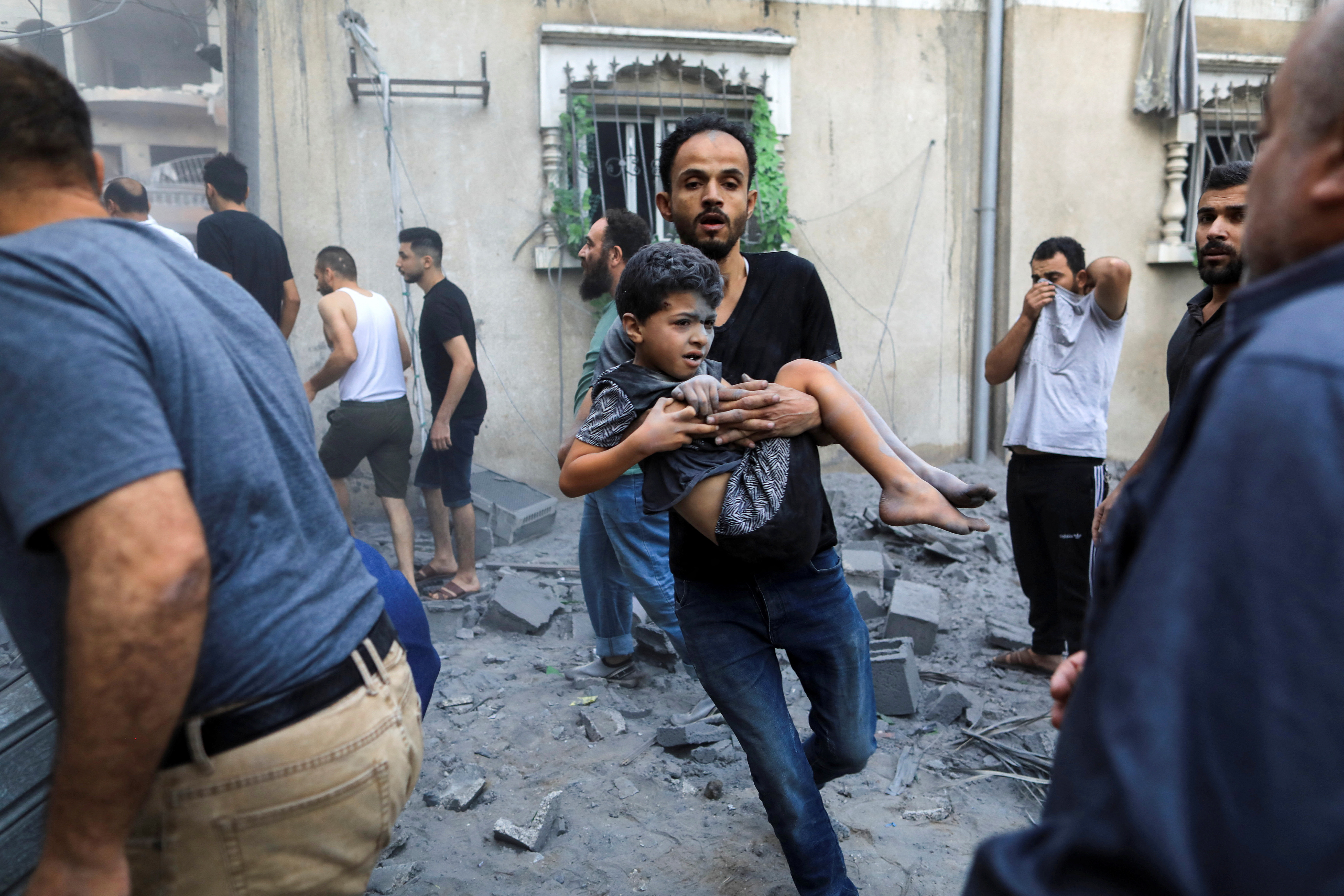 A man carries a wounded child at the site of an Israeli strike in Khan Younis in the southern Gaza Strip October 19