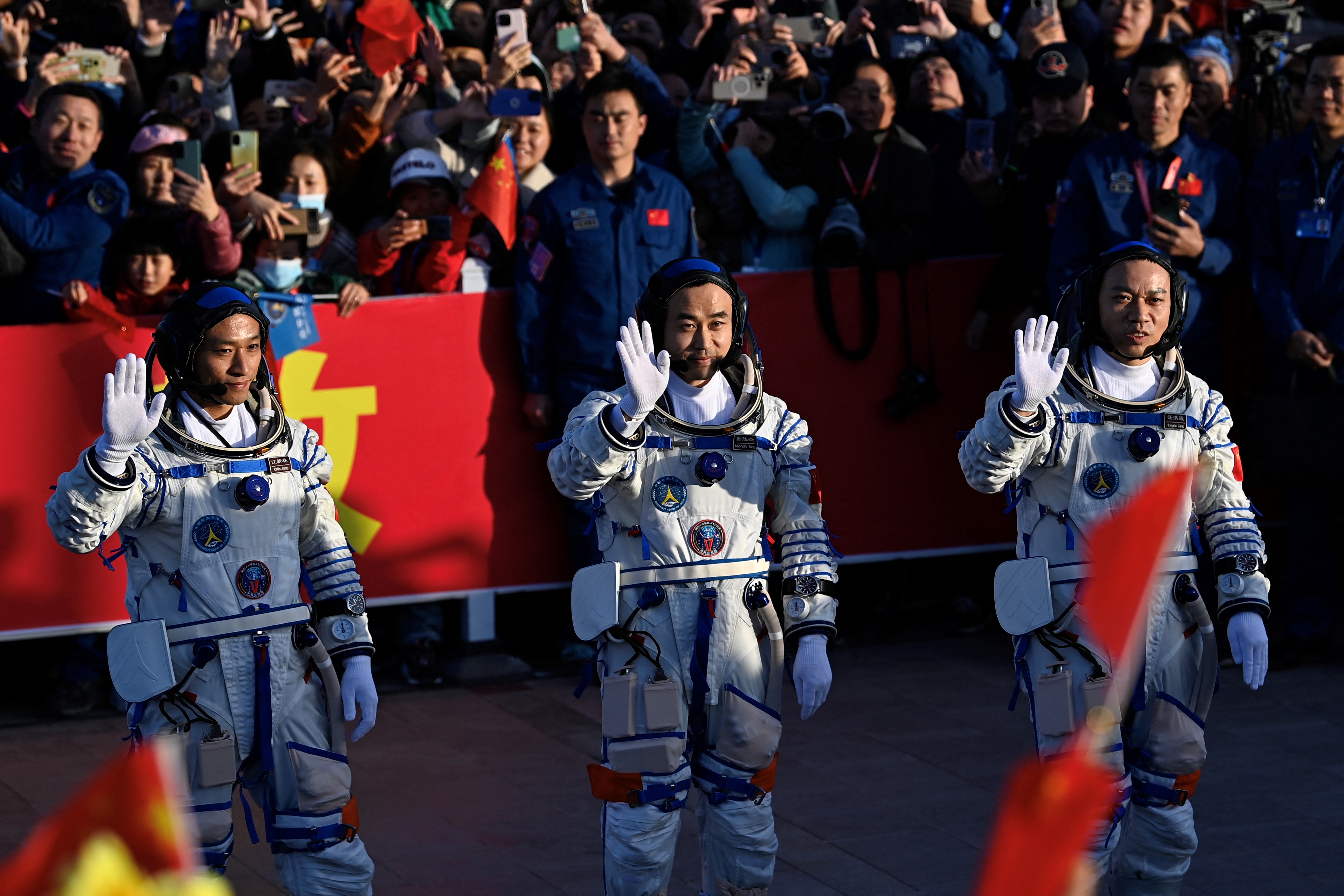 The three astronauts waving to the crowd before boarding the space ship
