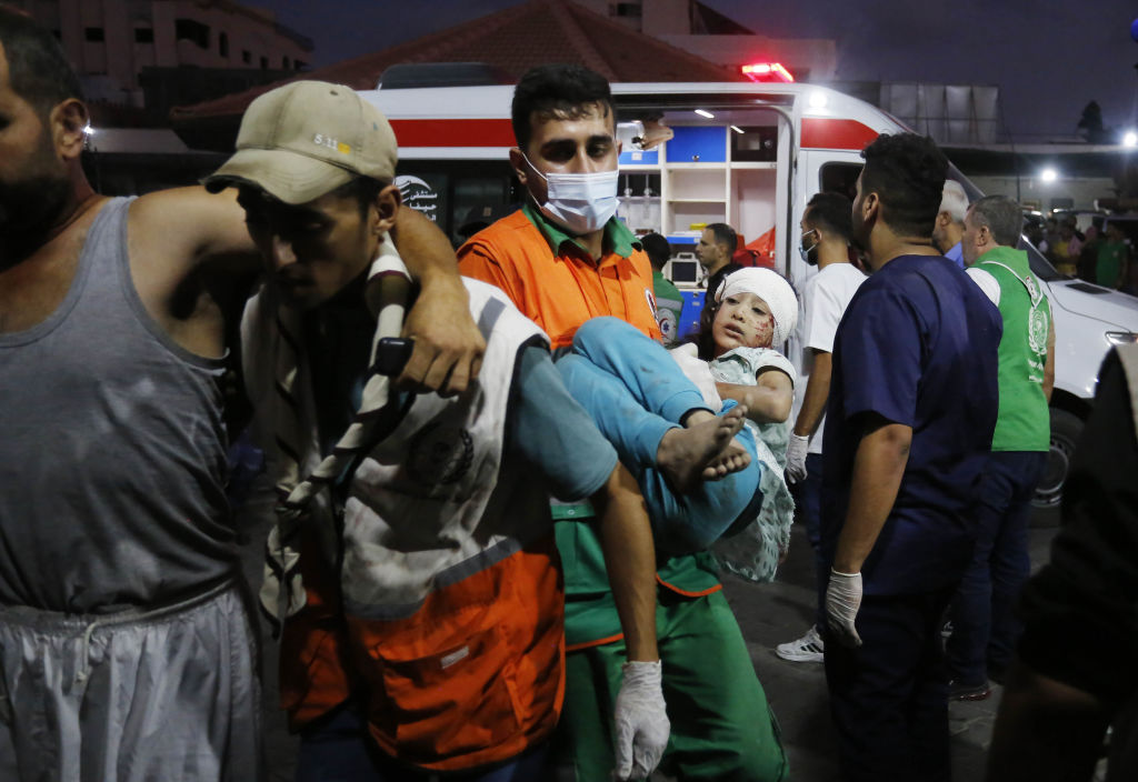 GAZA CITY, GAZA - OCTOBER 11: A health officer carries an injured child to the Al-Shifa Hospital as Israeli airstrikes continue on the fifth day in Gaza City