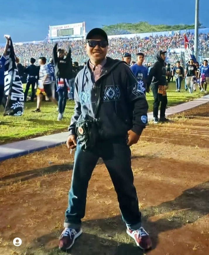 Rini Hanifa’s son Agus Rian Syah Pratama Putra before the match. He's standing on the pitch. He looks happy and excited.