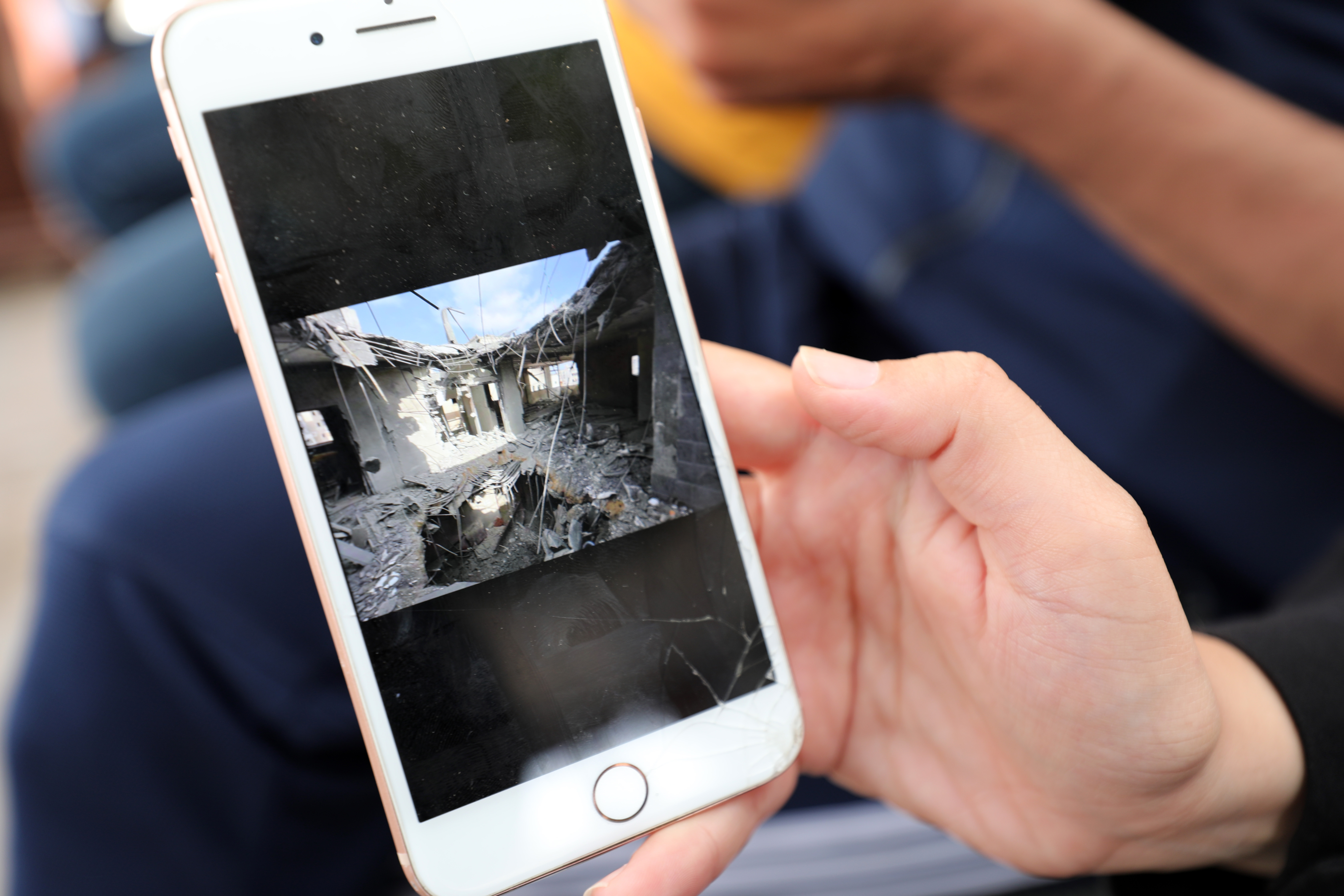 Al-Khalidi shows pictures on her phone of her destroyed home that was hit in an Israeli attack