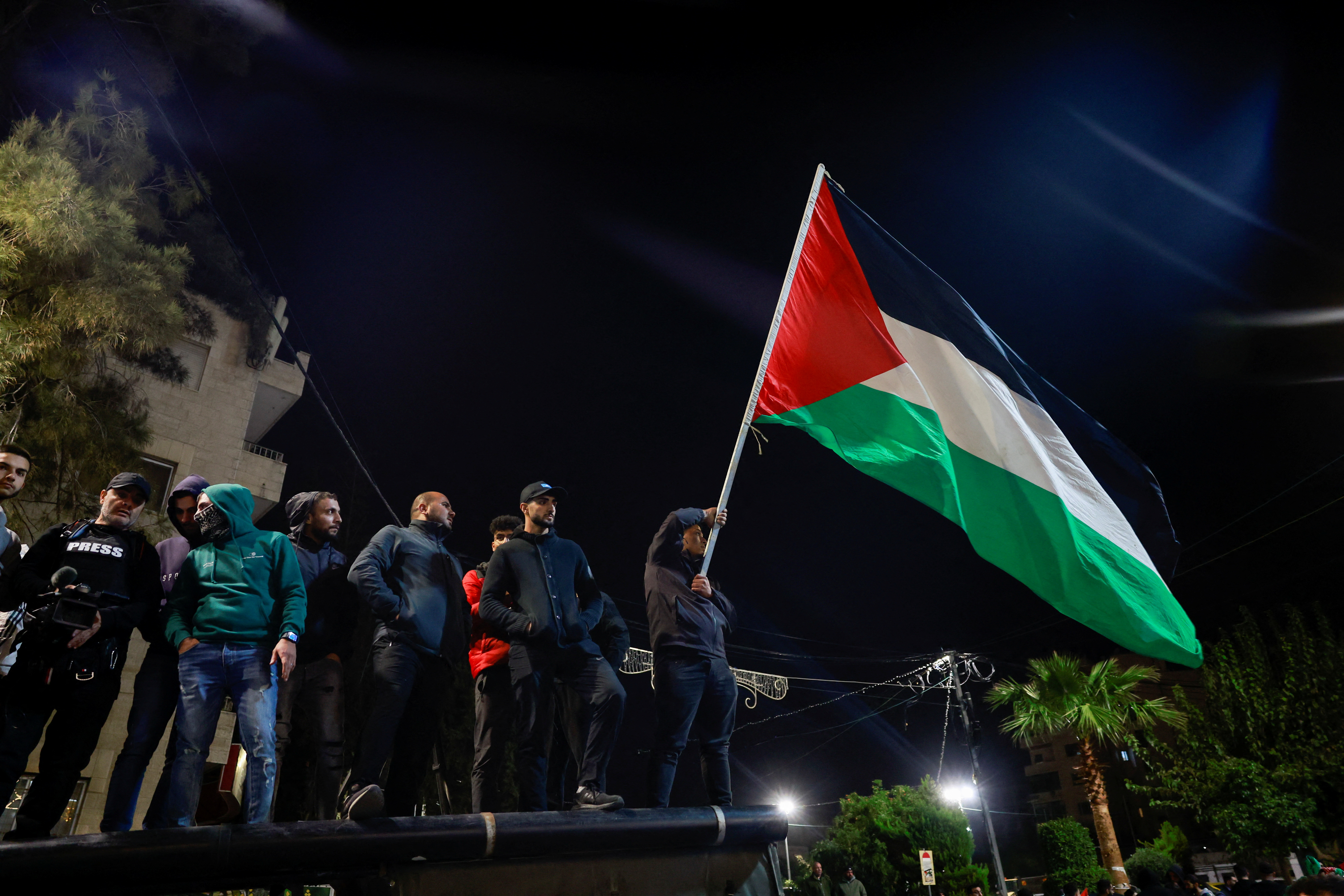 People wave the Palestinian flag as Palestinian prisoners leave after being released from the Israeli military prison, Ofer, amid a hostages-prisoners swap deal between Hamas and Israel, near Ramallah in the Israeli-occupied West Bank November 26
