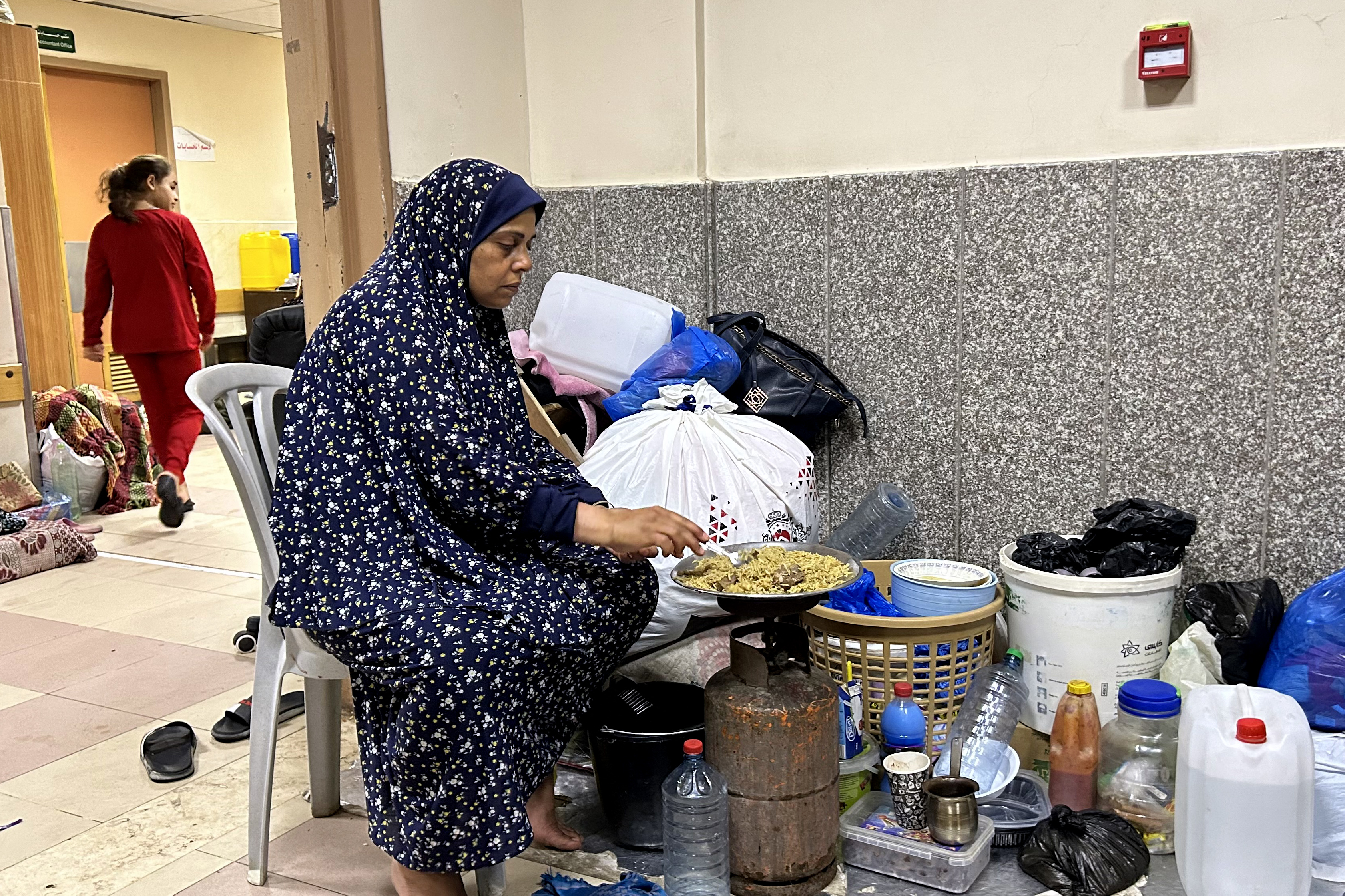 An internally displaced woman cooks while camping at Al-Shifa hospital in Gaza City