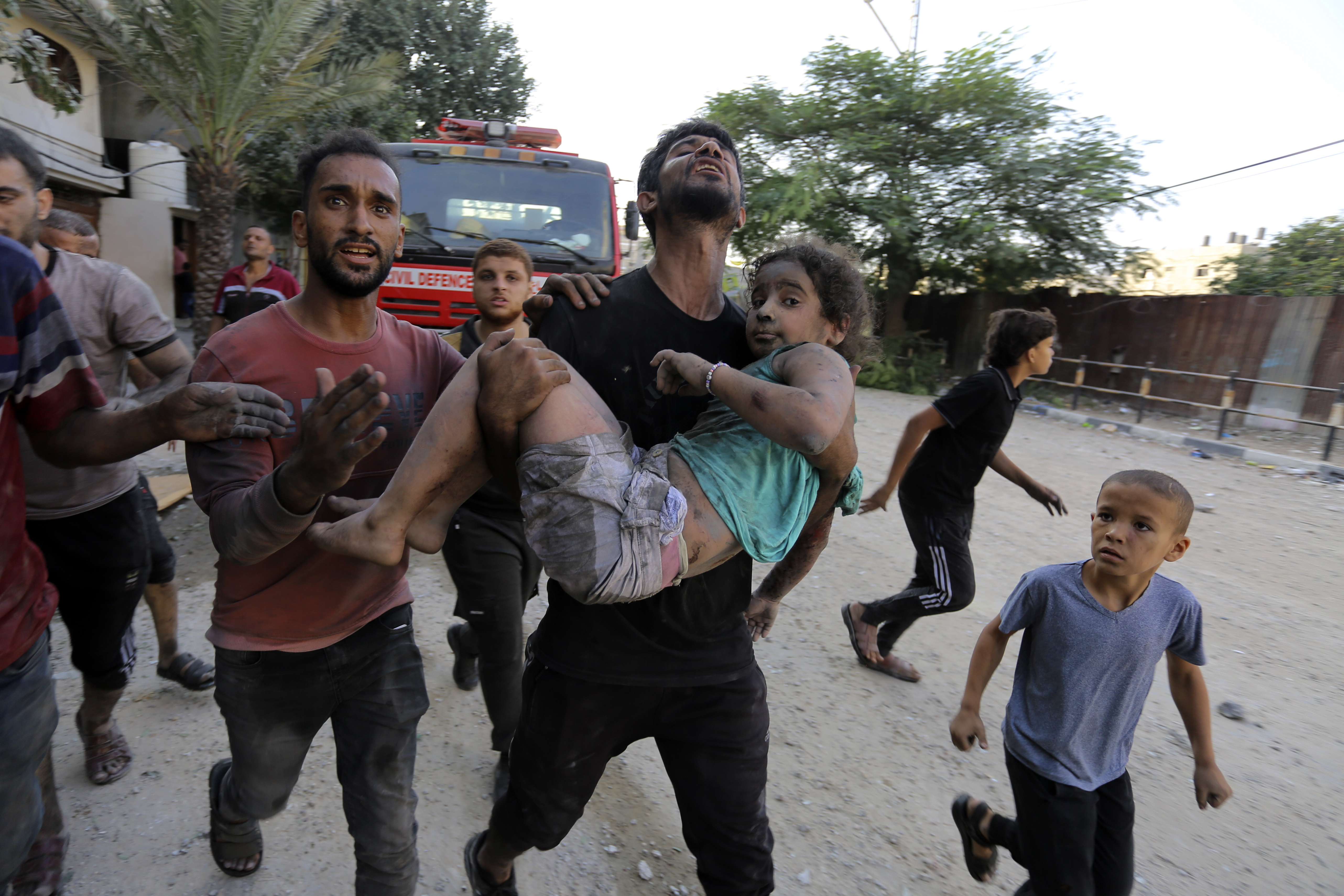 Palestinians carry a wounded girl after being rescued from under the rubble of buildings that were destroyed by Israeli airstrikes in Jabaliya refugee camp, northern Gaza Strip