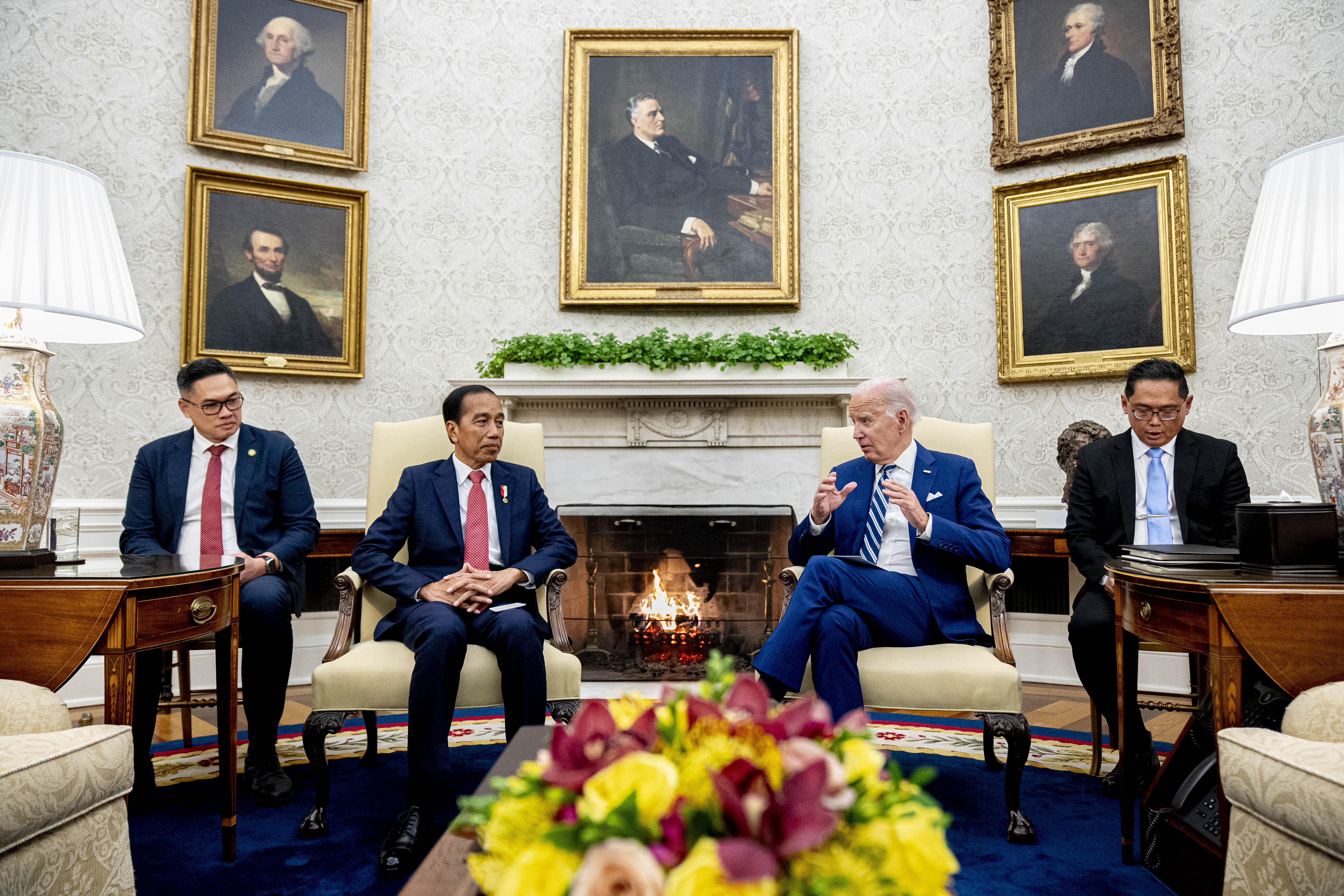 Joe Biden and Joko Widodo, each with an aide, in the Oval Office. There are portraits of five former presidents on the wall behind them. The main one above the fireplace is of Franklin D Roosevelt