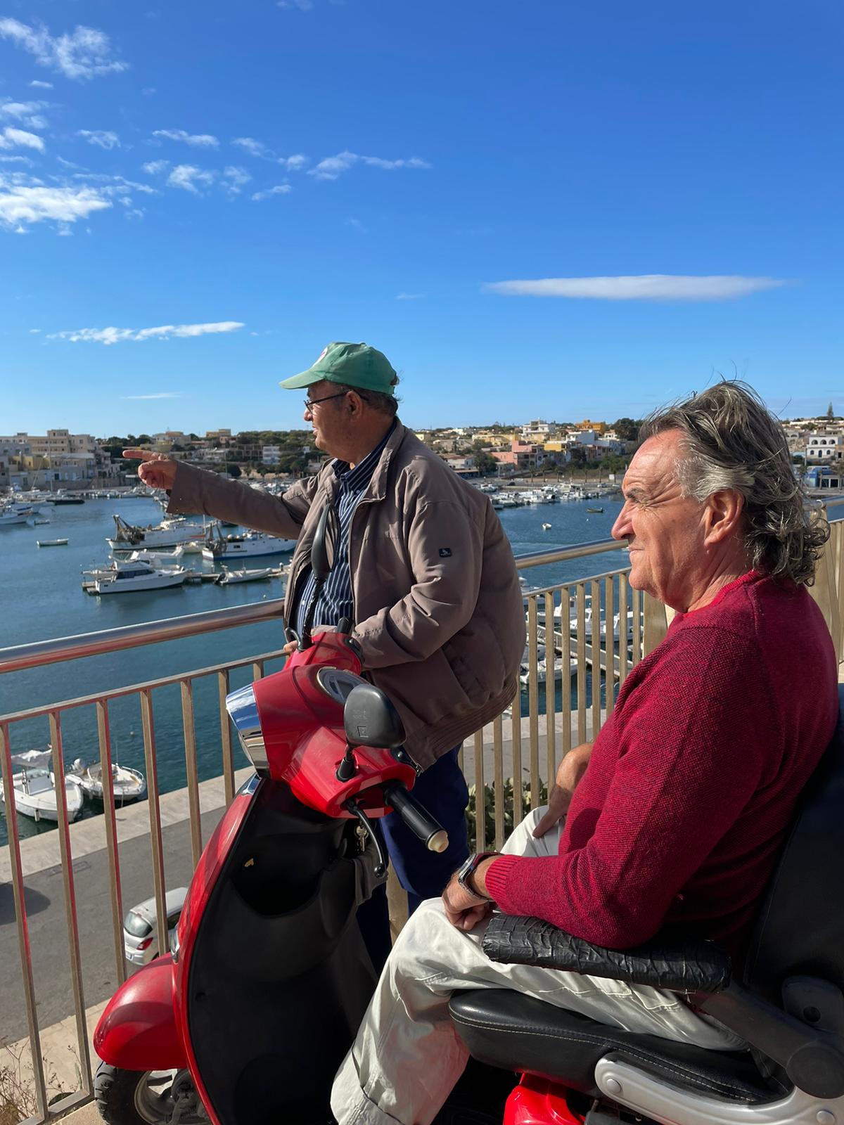 Vincenzo, left, and Michele watch the Lampedusa harbour from the end of the main street on the island, Via Roma