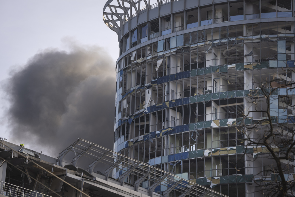 Smoke rises behind a building damaged in Russia’s missile attack in Kyiv, Ukraine, on Friday, December 29
