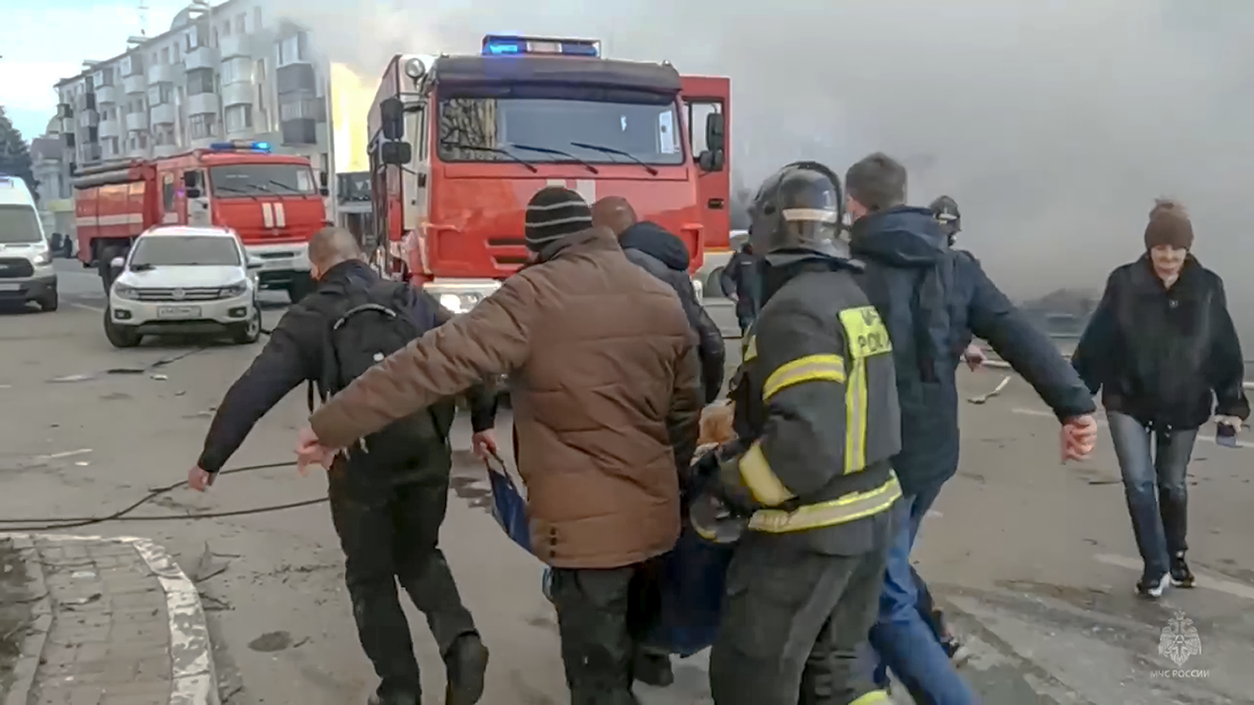 Rescuers and people carry a wounded person after shelling in Belgorod