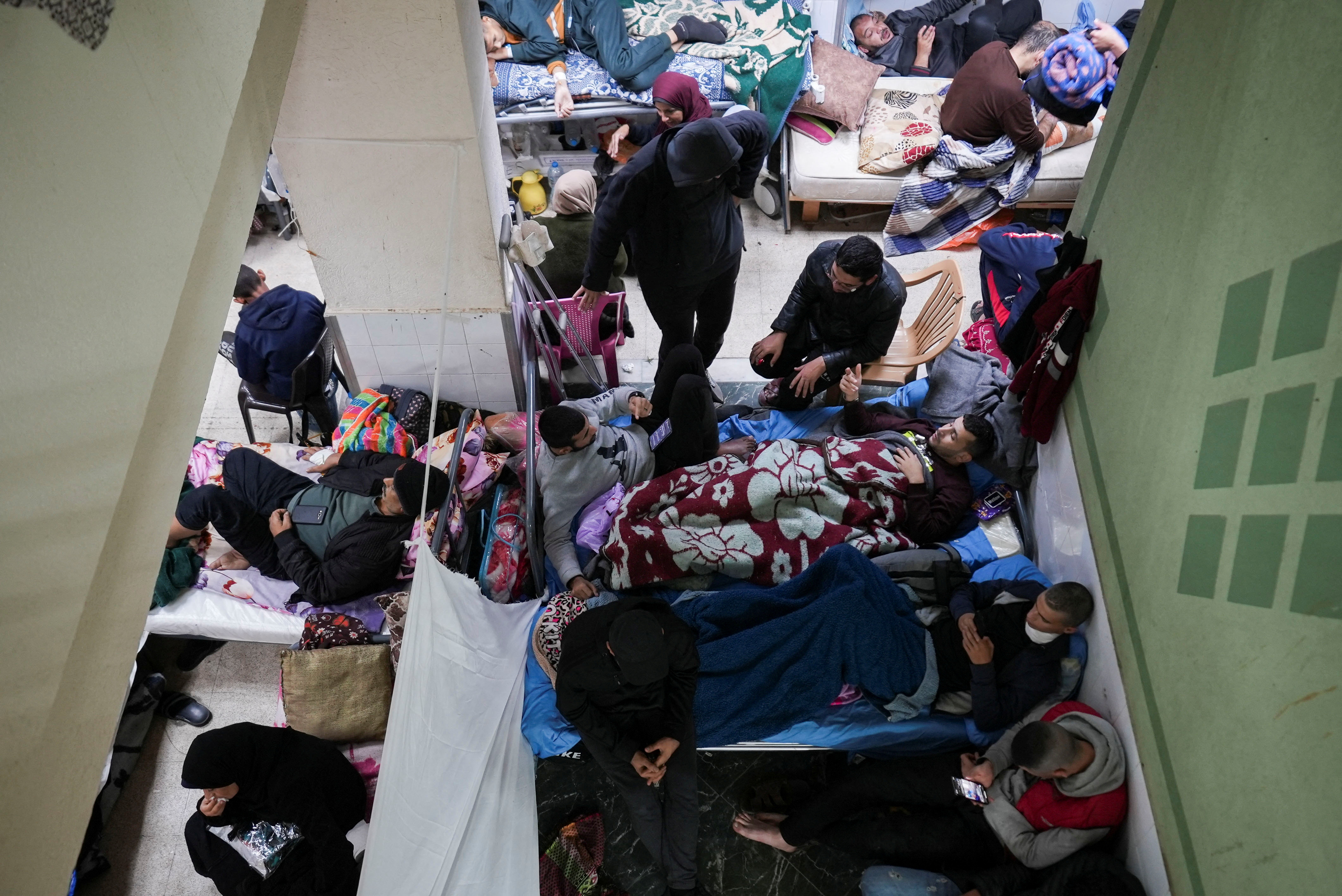 Palestinians wounded in Israeli strikes lie on beds as displaced people shelter at Shuhada Al-Aqsa Hospital, amid the ongoing conflict between Israel and Hamas, in Deir Al-Balah in the central Gaza Strip.