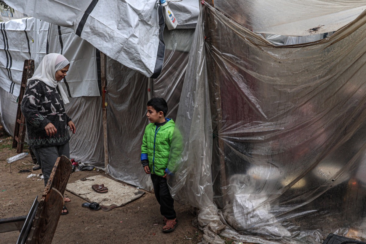 Displaced Palestinians sit behind a plastic sheet in the zoo in Rafah in the southern Gaza Strip.