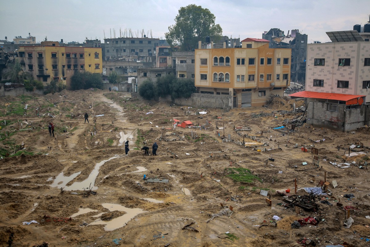 People walk at a makeshift cemetery, parts of which the Israeli army reportedly bulldozed to exhume bodies