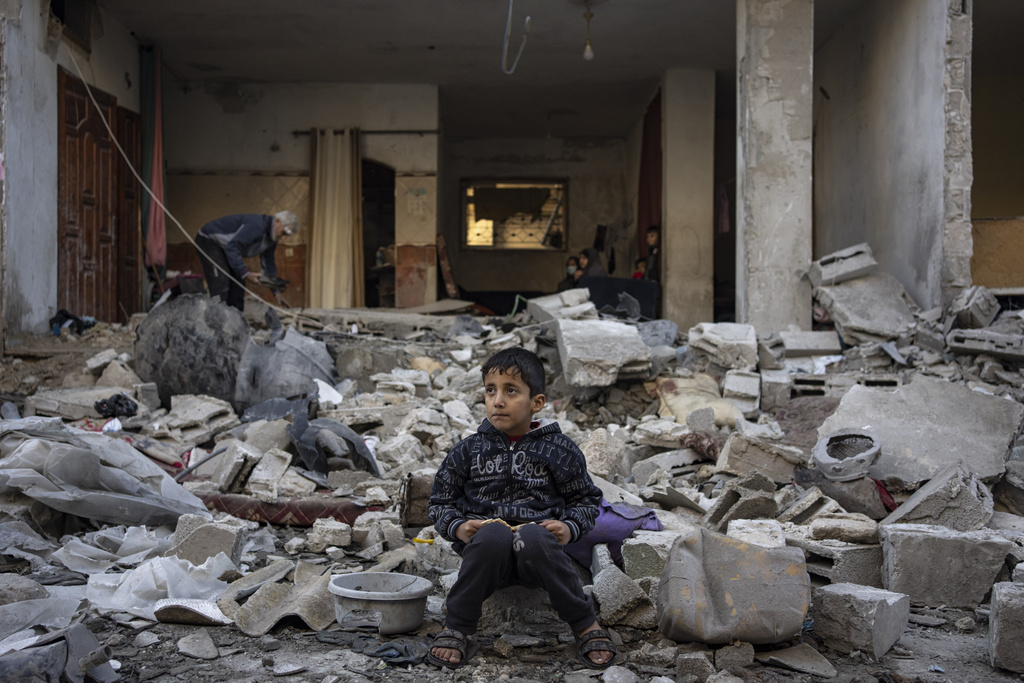 A Palestinian boy sits on the rubble of a destroyed building after an Israeli strike in Rafah, southern Gaza Strip