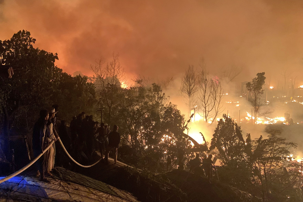 Rohingya refugees watch a fire blaze in a Bangladesh refugee camp