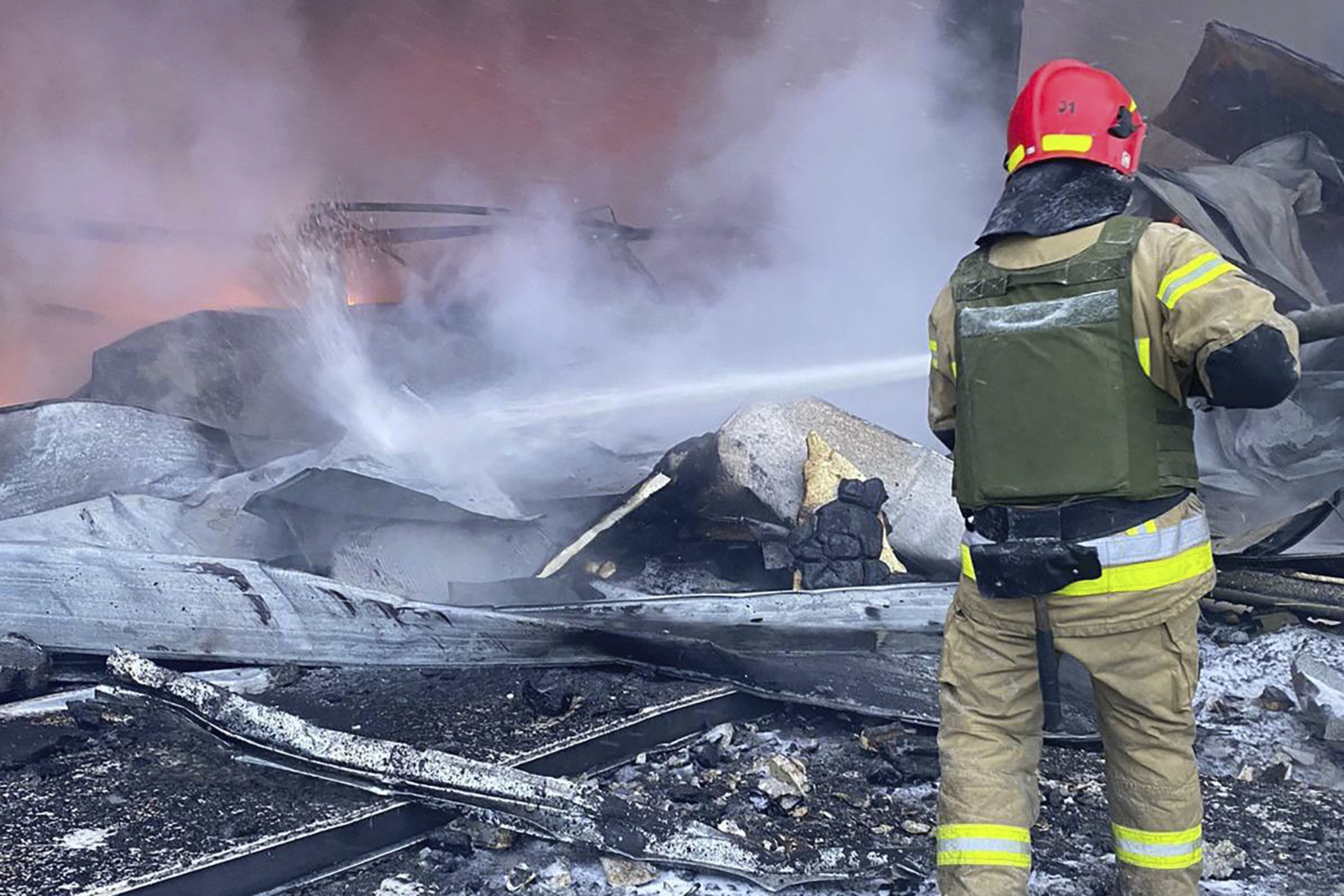 a firefighter works to extinguish a fire after a Russian missile