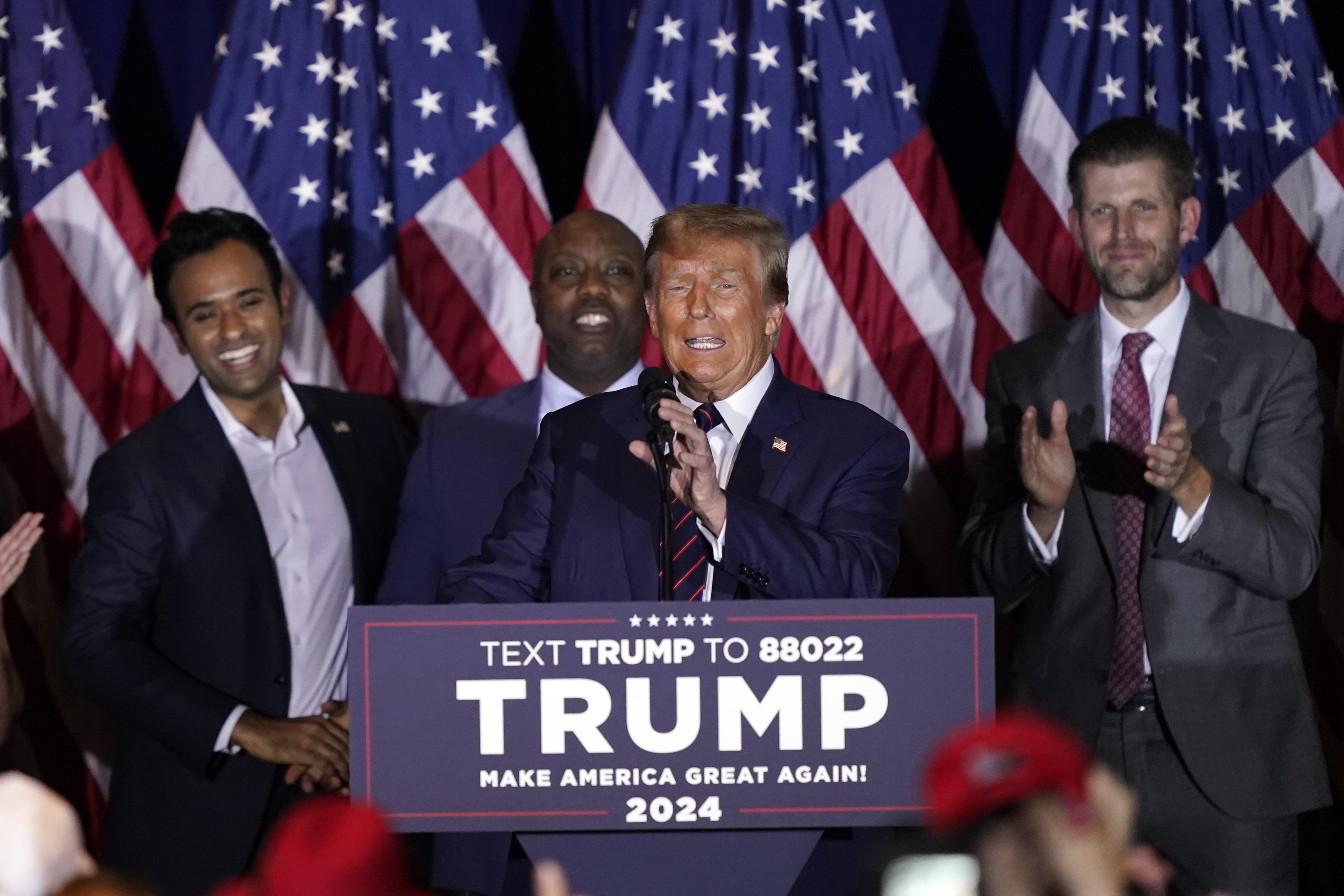 Former President Donald Trump speaks at a primary election night party in Nashua, NH, as Vivek Ramaswamy, Senator Tim Scott and Eric Trump laugh