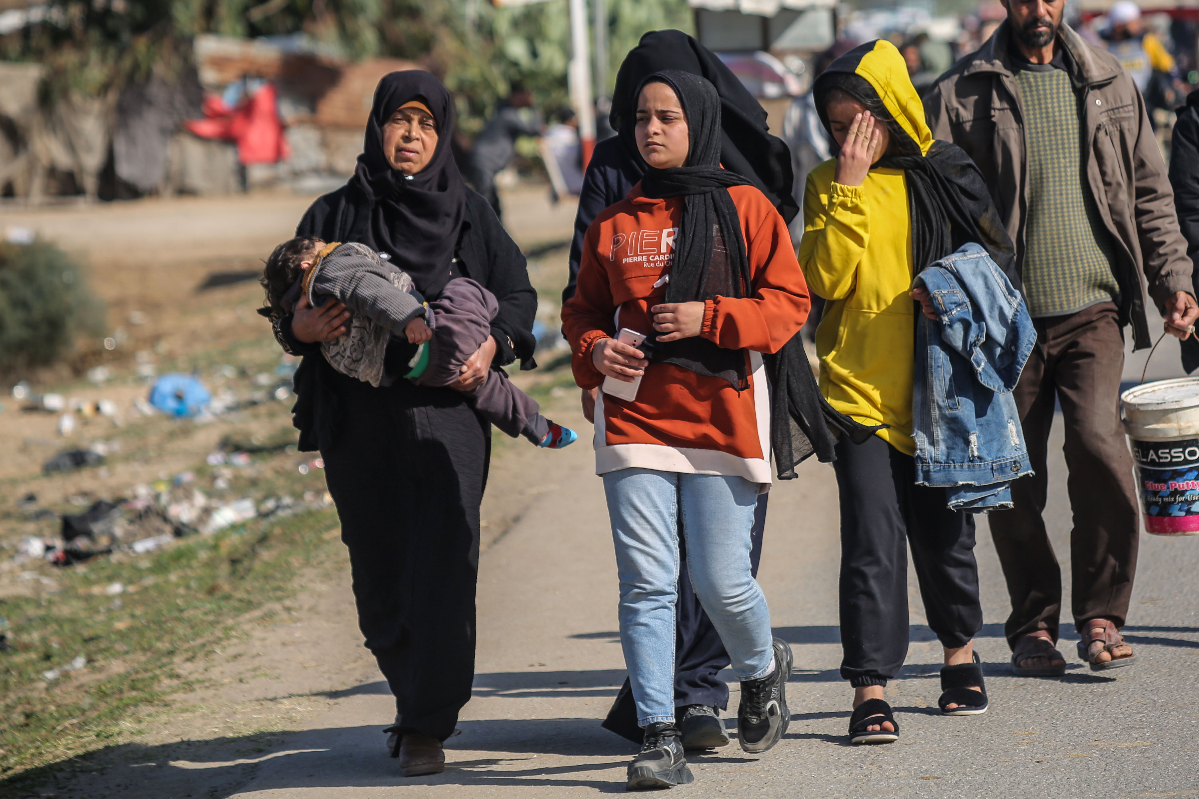Woman carrying an exhausted baby fleeing on foot from Israeli bombs