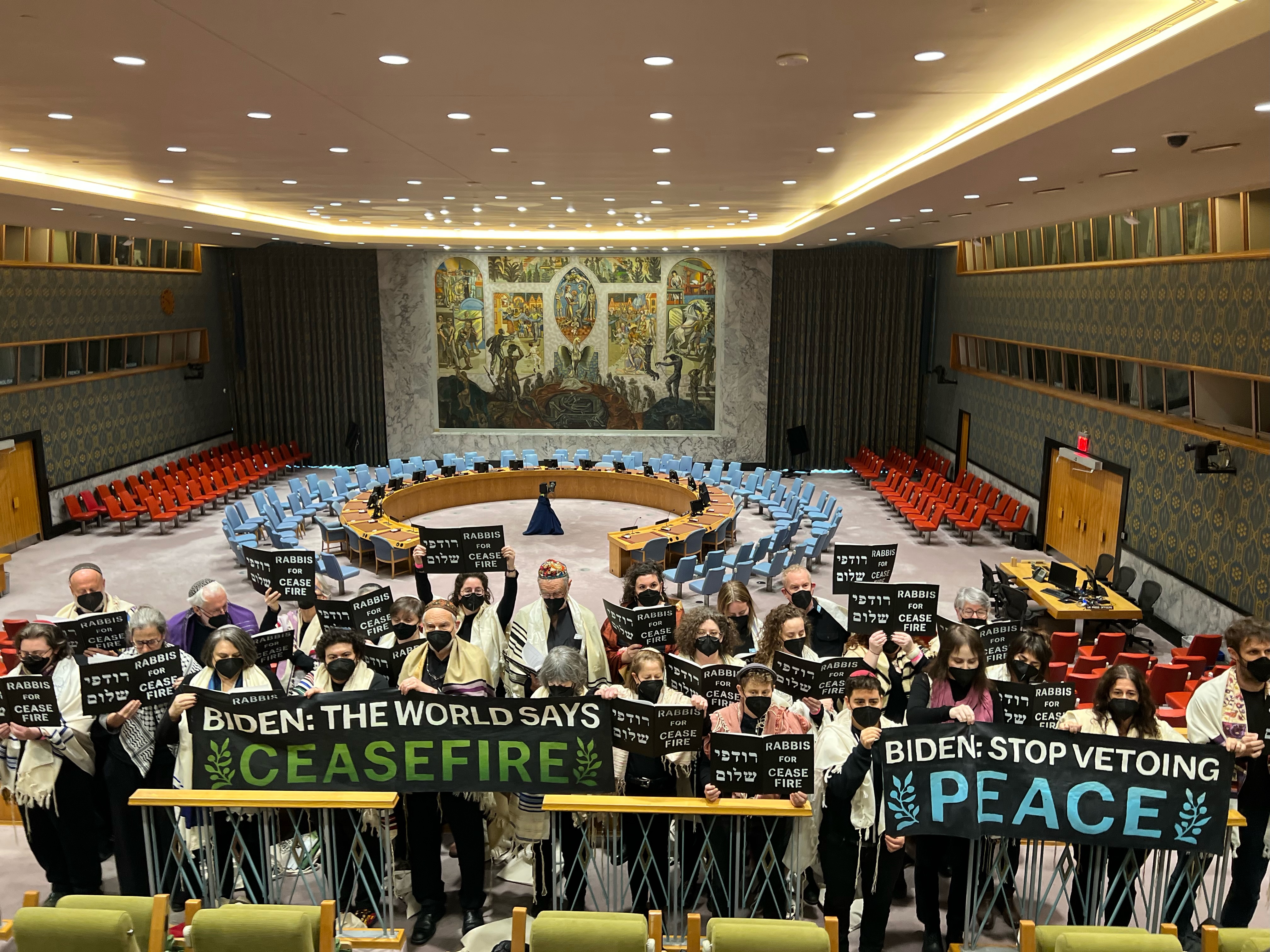 A photo of rabbis in UN Headquarters call holding prayer books and posters reading Biden, the world says Ceasefire Now
