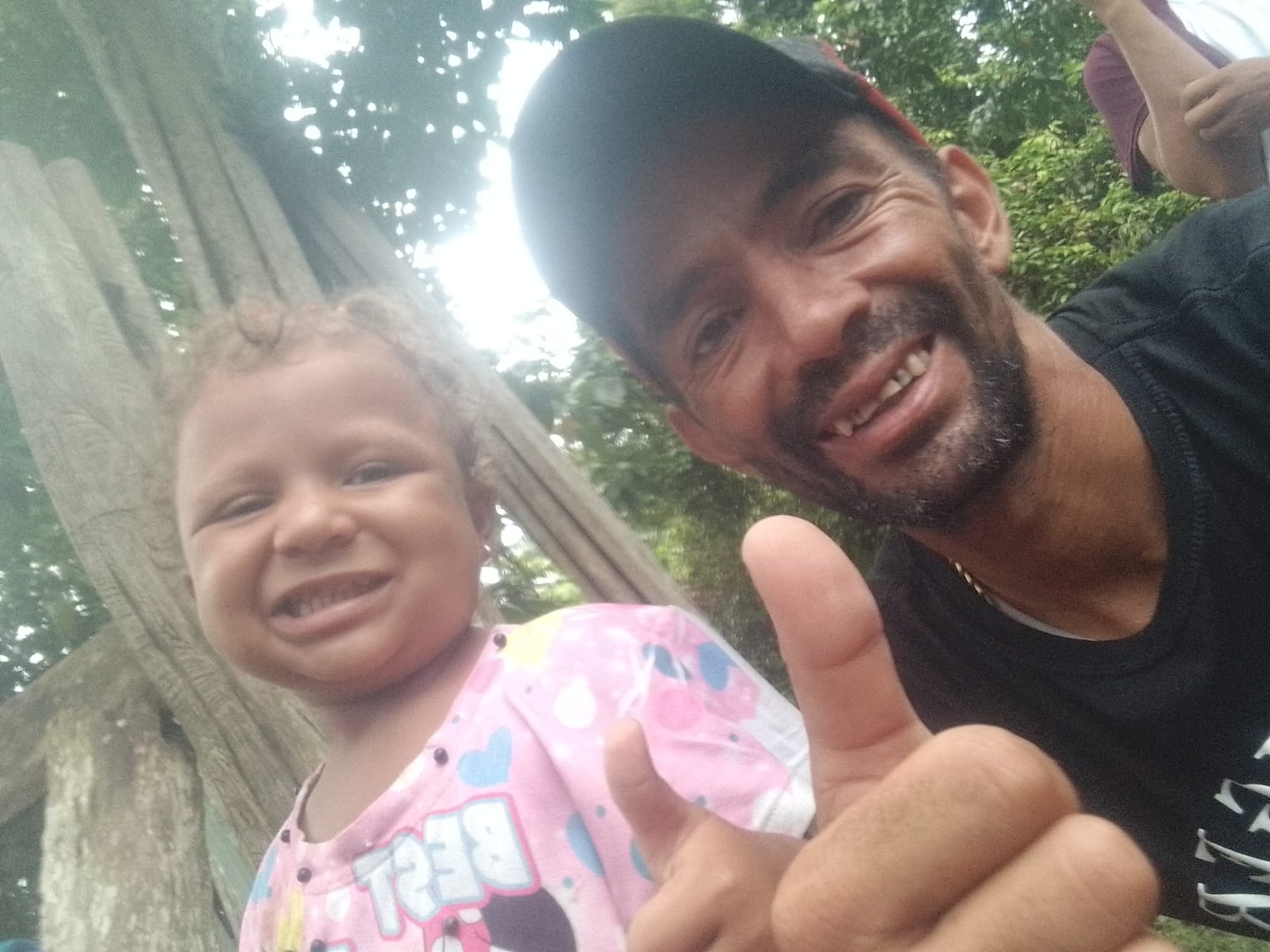 Emiliannys — a little girl in a pink T-shirt — and her father Victor Hidalgo Lopez, who wears a ballcap and flashes a thumbs-up at the camera.
