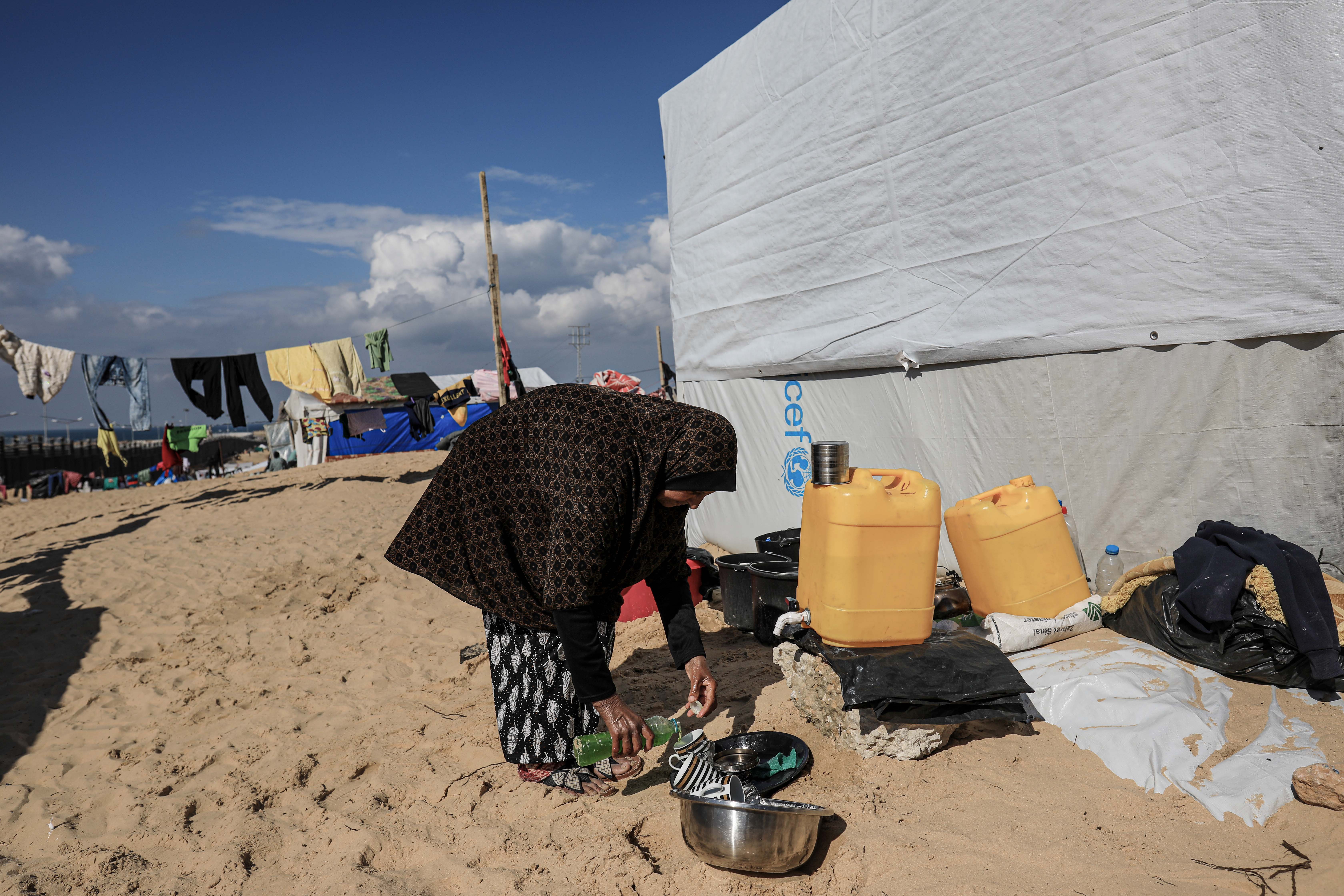 Woman getting small amounts of water from public dispenser