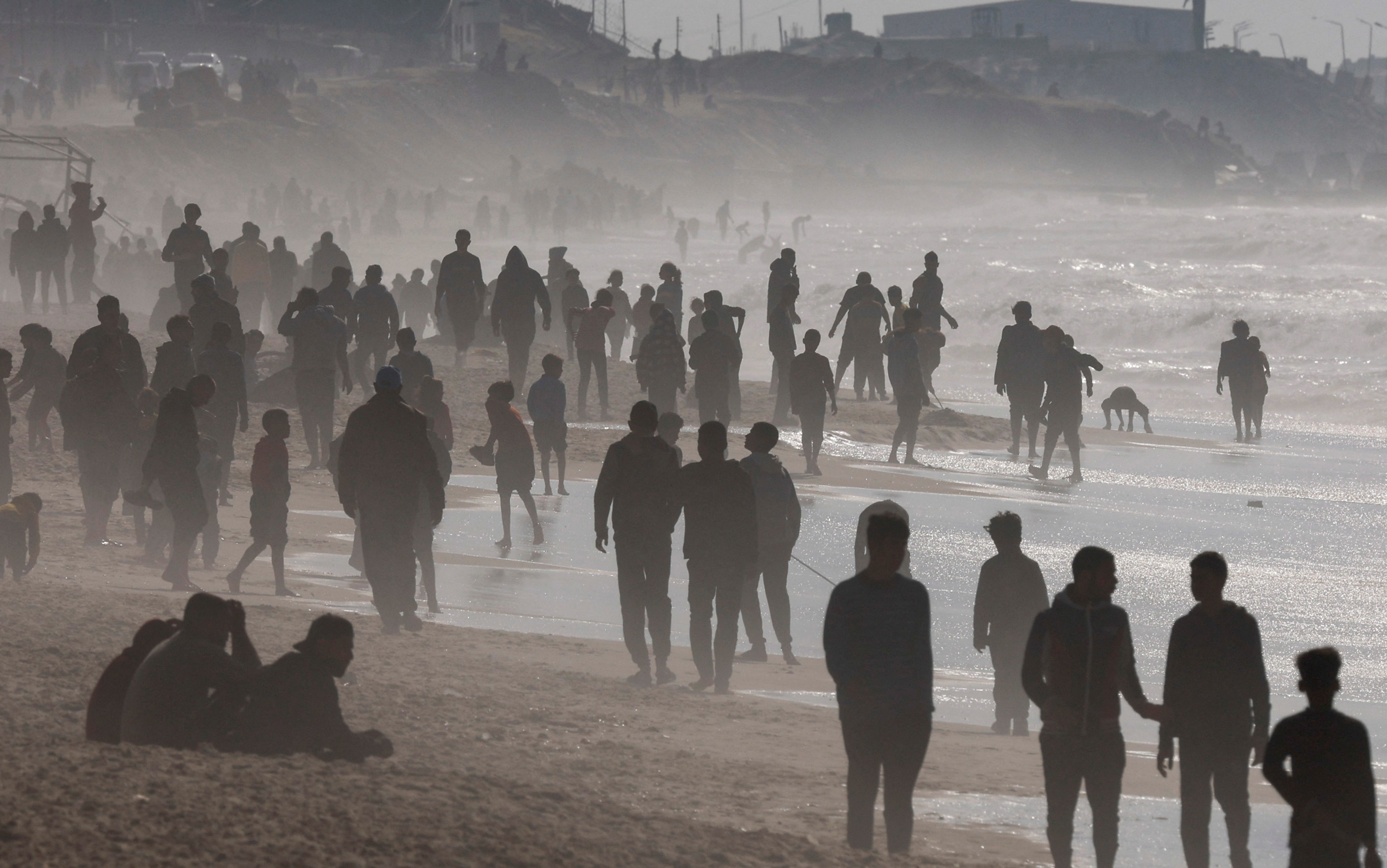Palestinians gather on a beach in the hope of getting aid air-dropped over Gaza