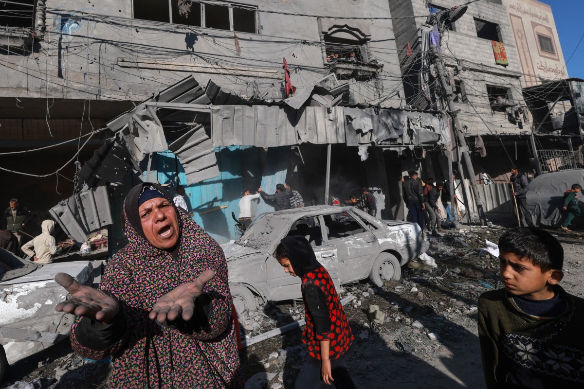 A Palestinian woman gestures near debris