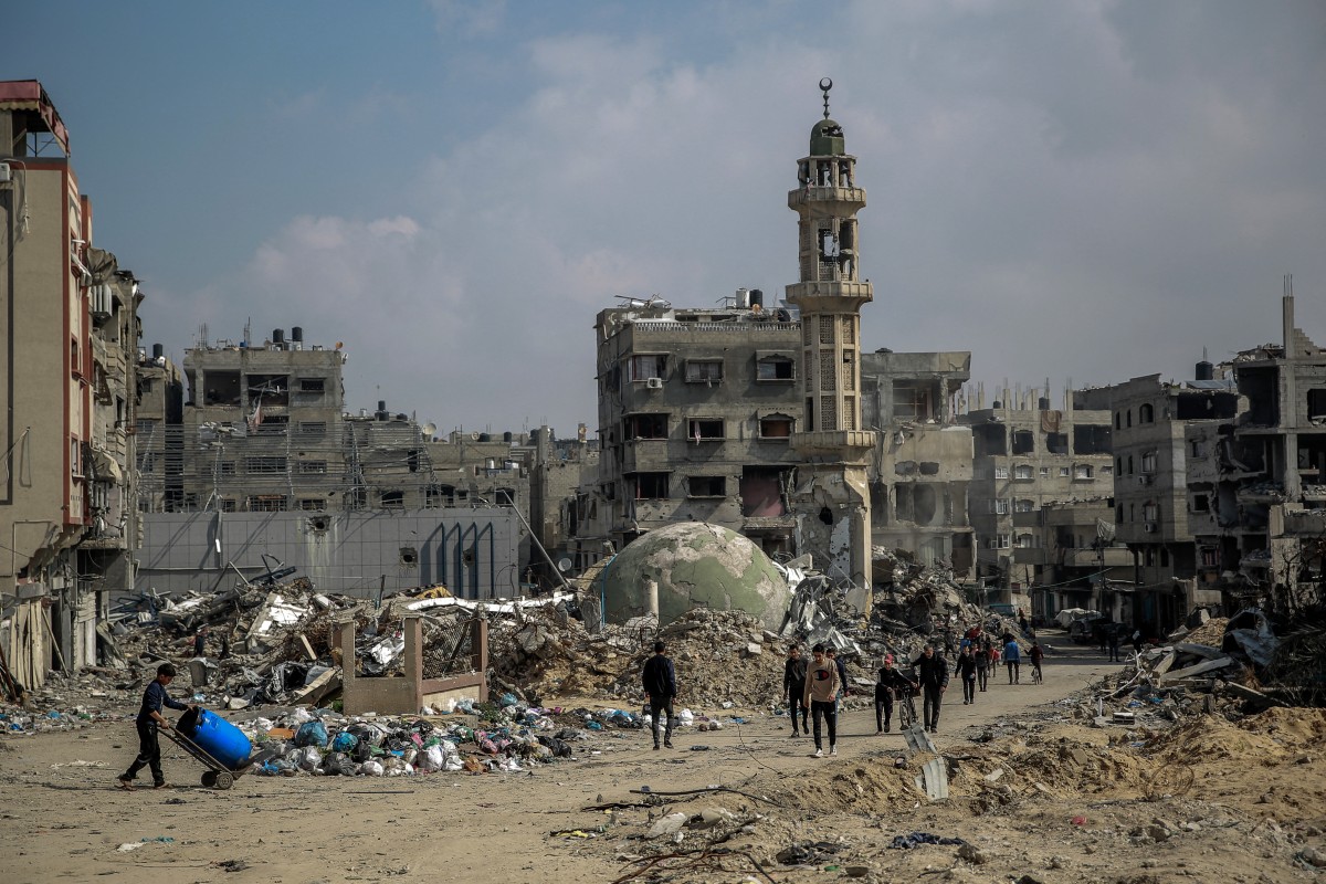 Palestinians walk amid debris of a mosque and buildings destroyed