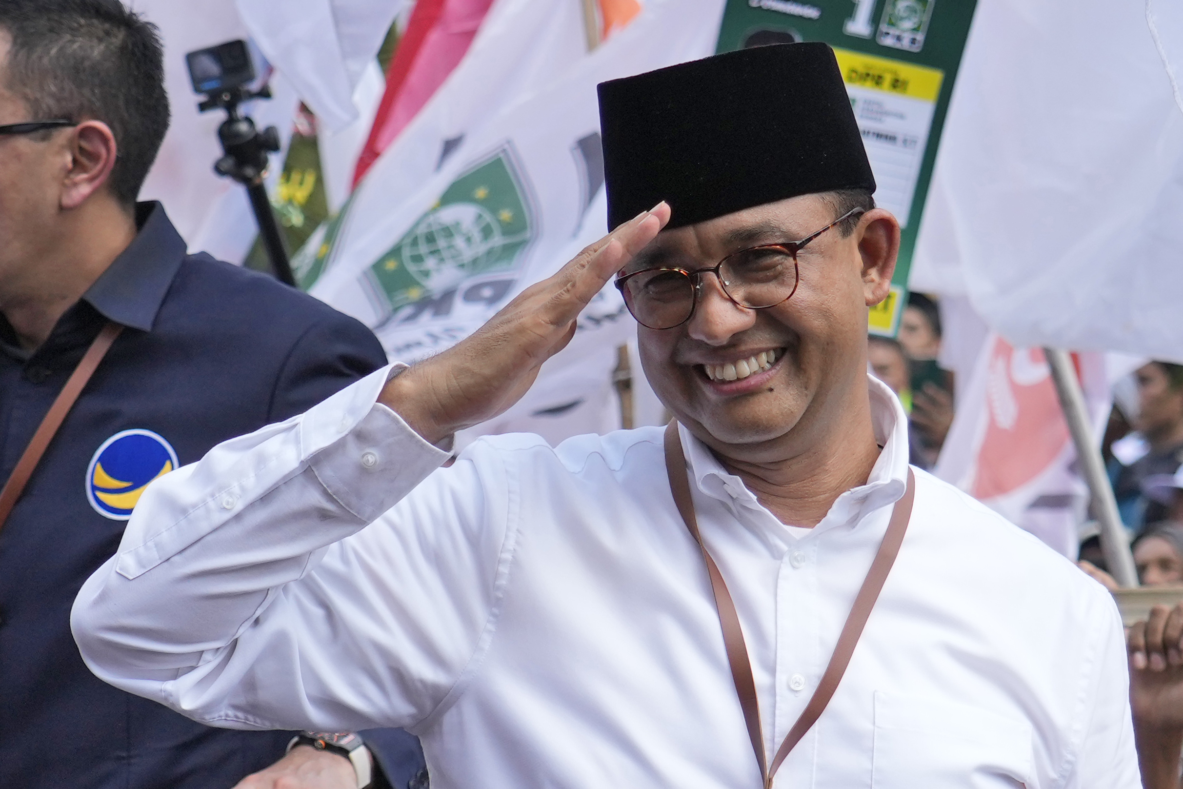 Anies Baswedan. He is saluting to the crowd and smiling