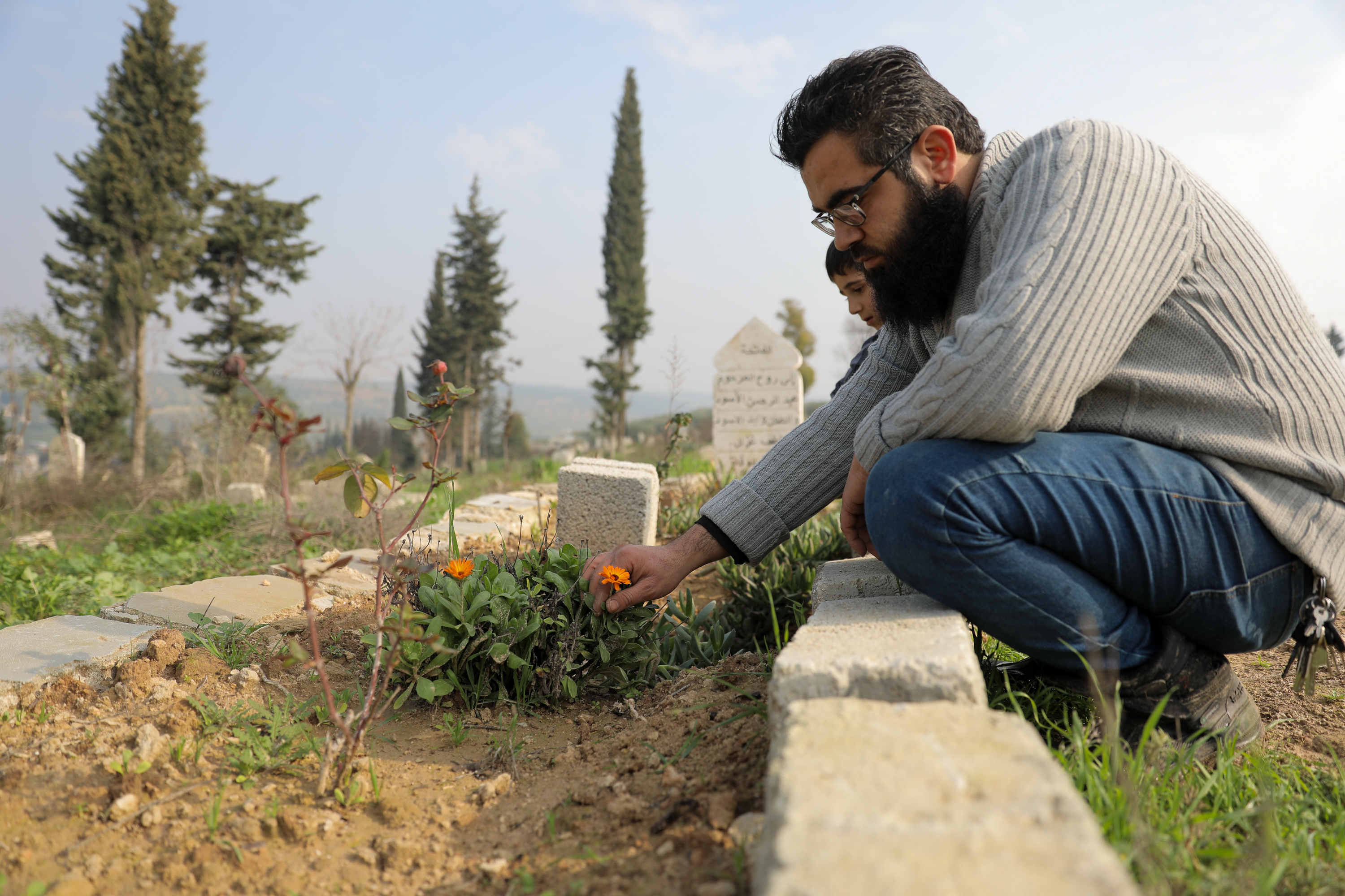 Ibrahim tends to his family’s nine graves, weeding and watering the flowers he planted