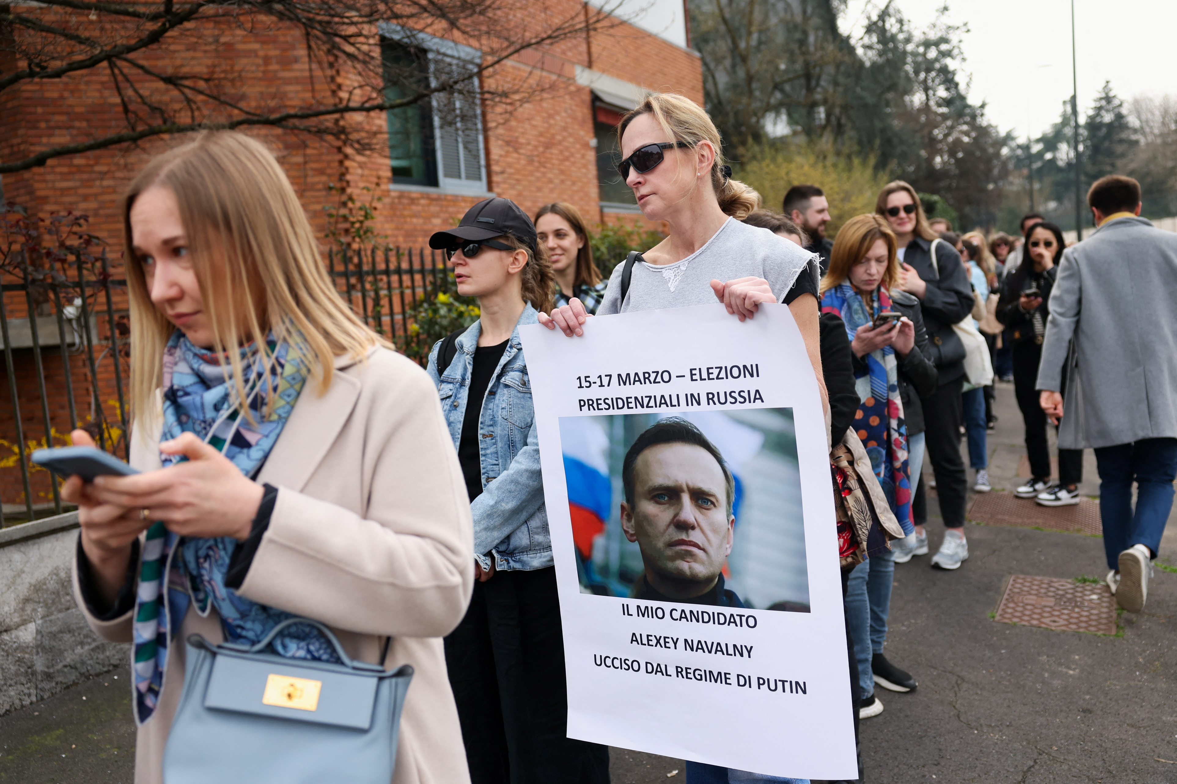 A woman holds a placard with a photo of late Russian opposition leader Alexei Navalny [File: Claudia Greco: Reuters]