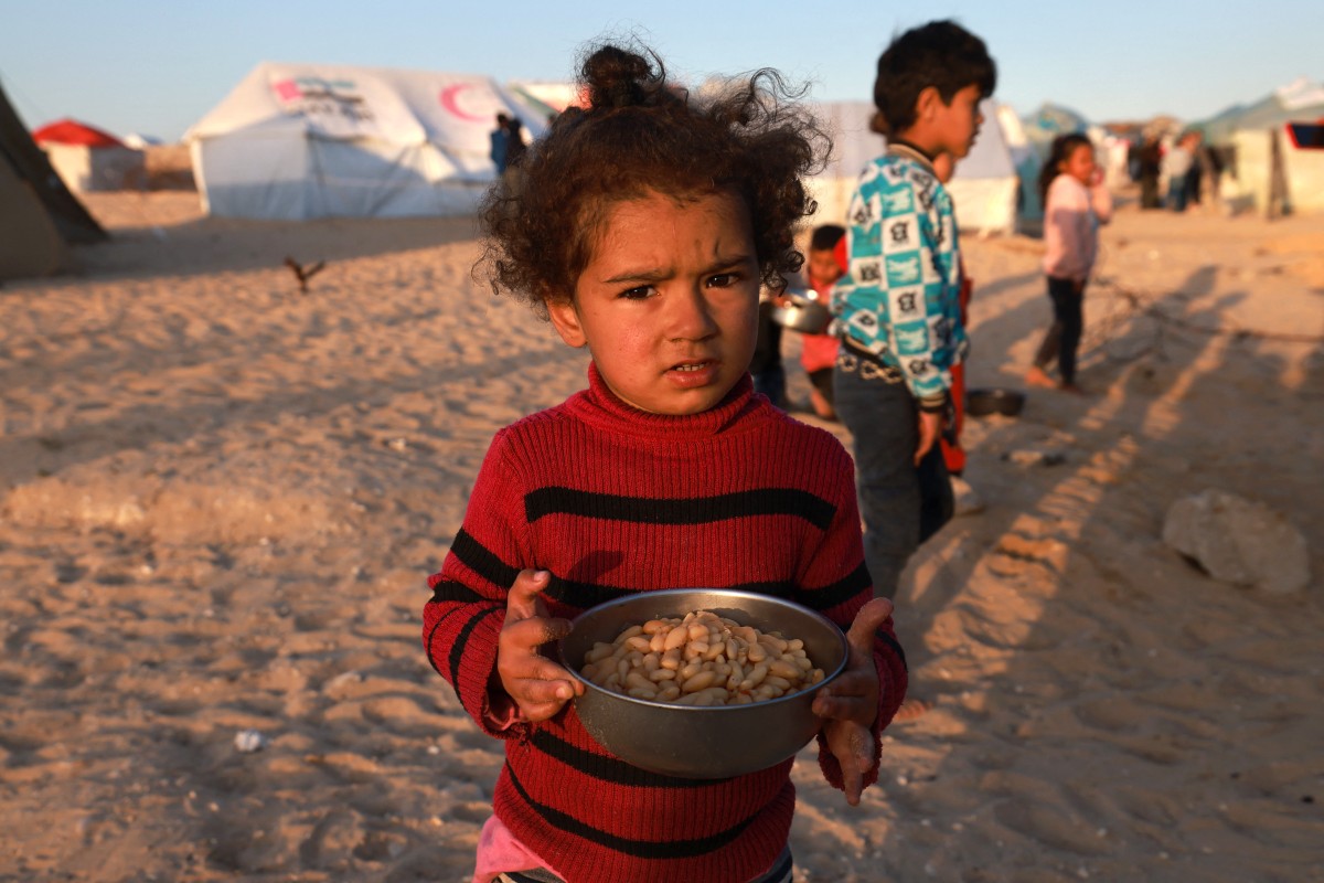 A Palestinian girl holds a bowl of beans before an iftar meal